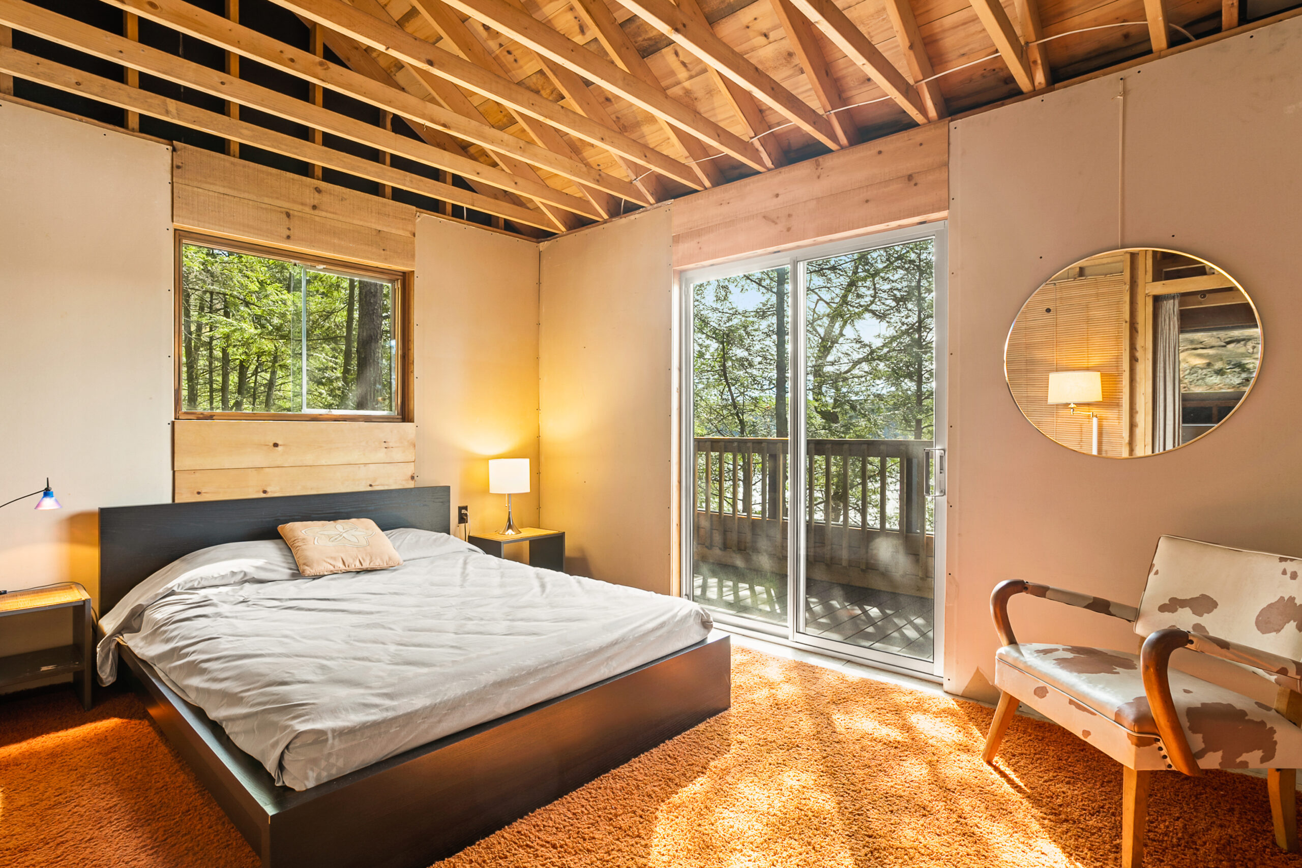 A large white bed in a wood panelled room with glass sliding doors