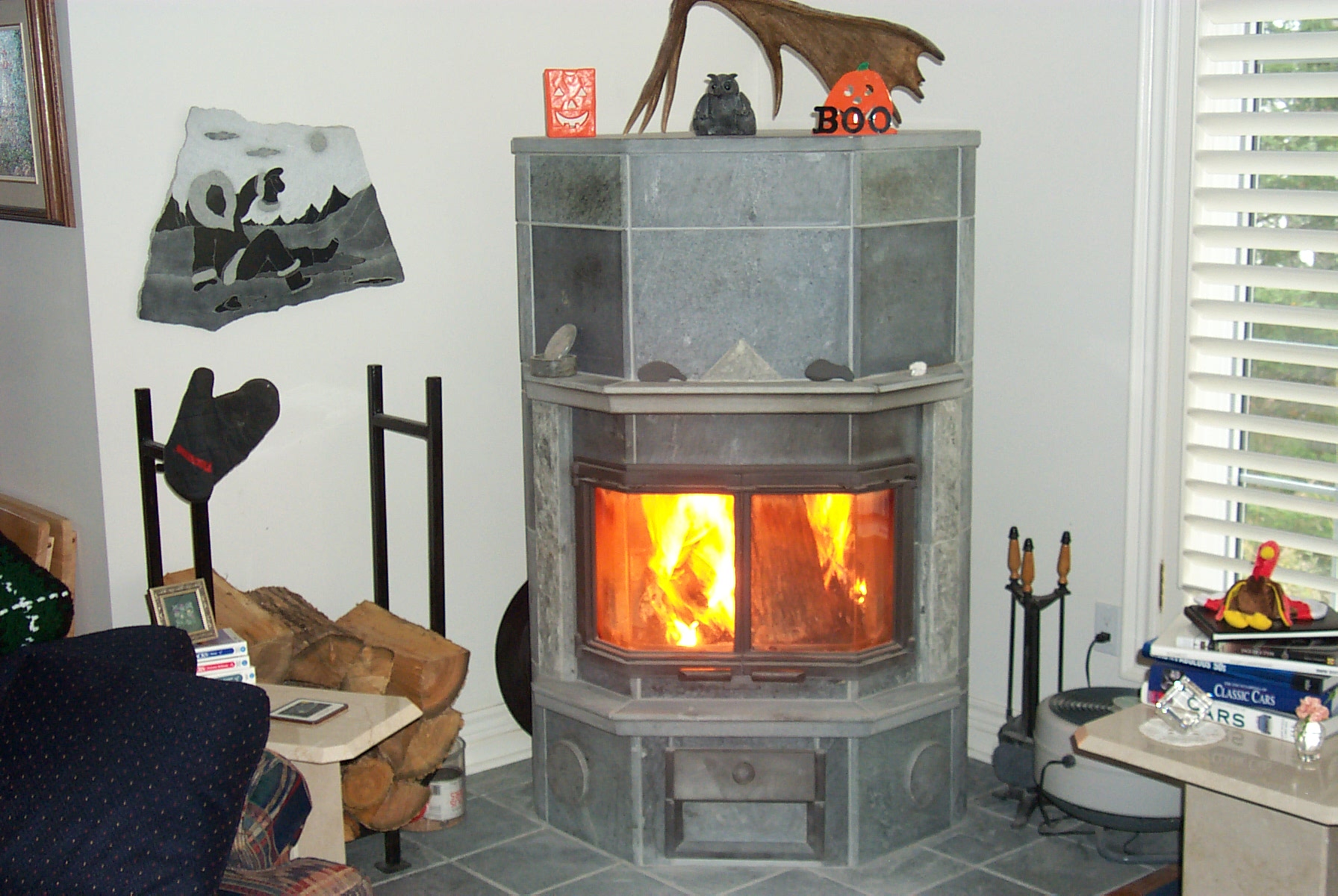 A grey stone woodstove has a fire burning