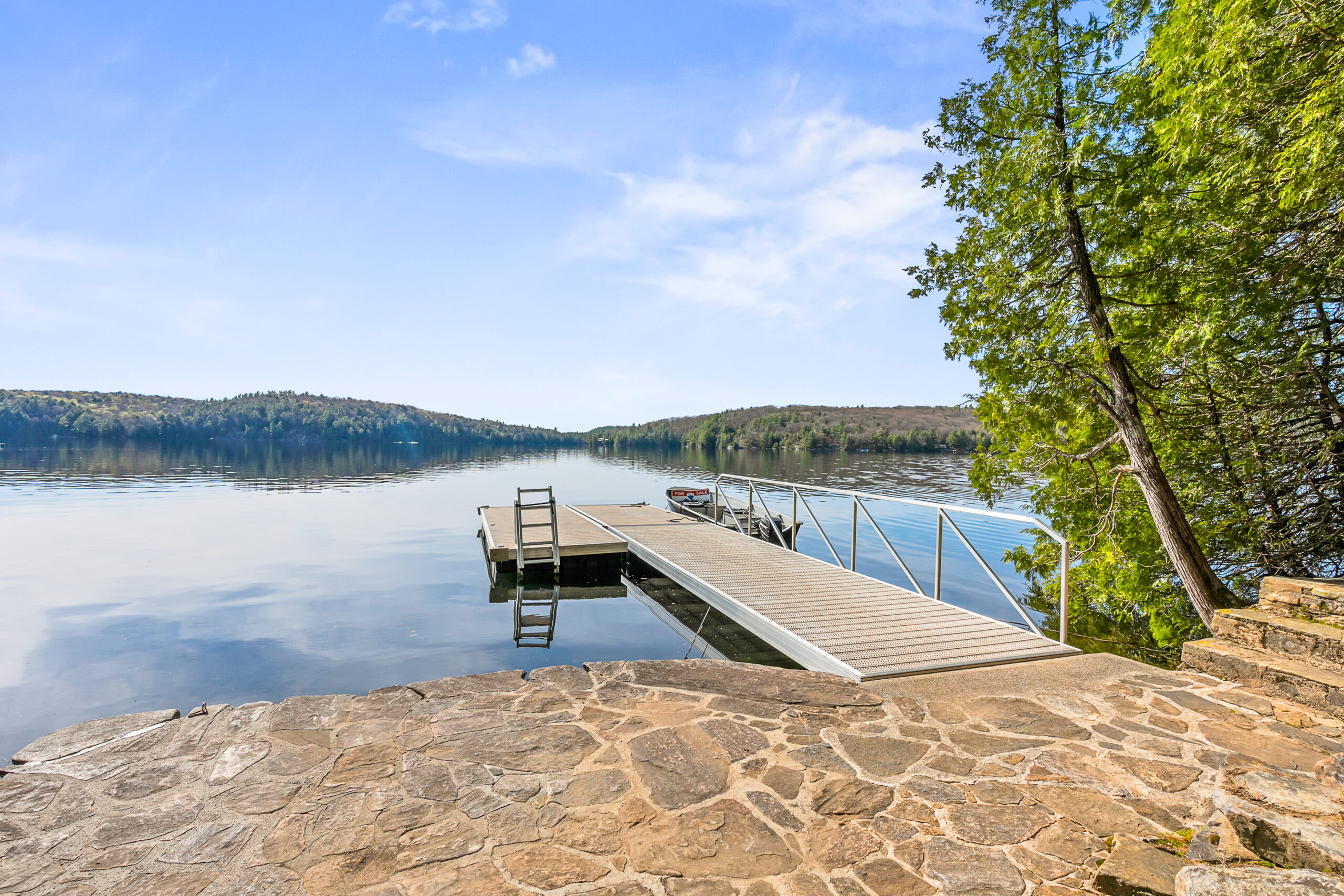 The stone patio leads out onto a large dock on the bright blue lake