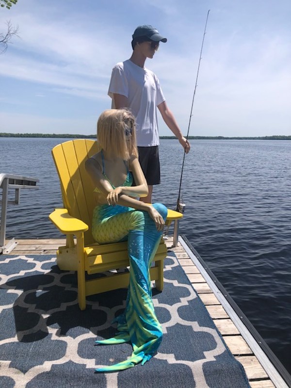 Two mannequins posed on a dock