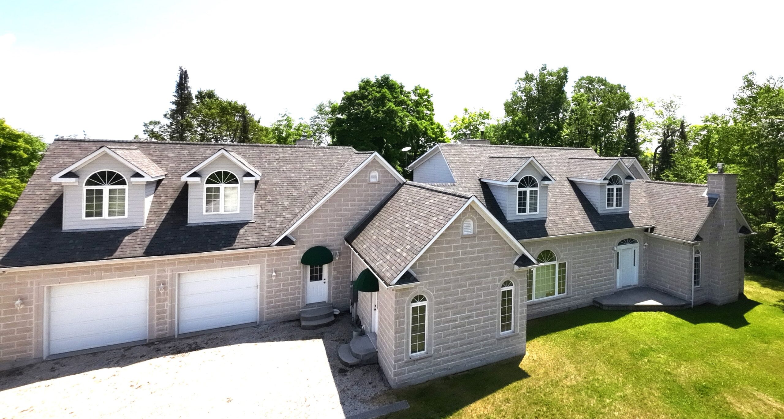 Aerial view of a grey house with a white garage door and front door