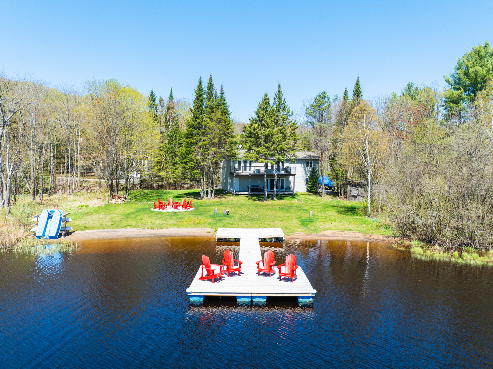 View from the front of the dock. The dock backs up onto wide greenspace and the brown cottage is nestled in the trees behind