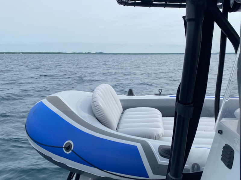 A blue and white inflatable boat sits on the edge of a police boat.