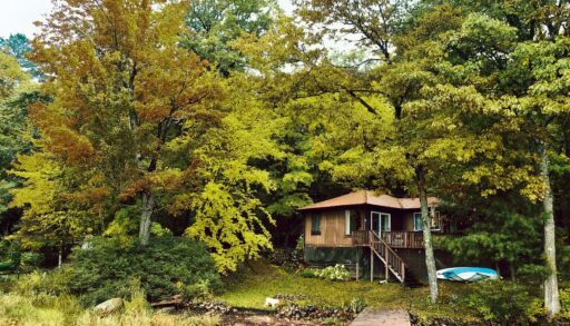 a photo of a waterfront cottage surrounded by trees