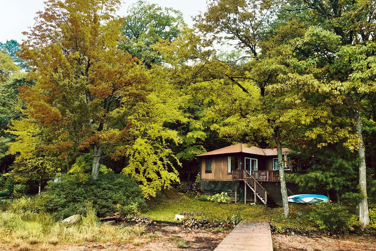 a photo of a waterfront cottage surrounded by trees