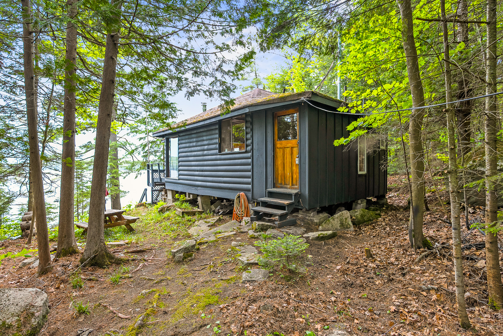 Front entrance of a dark grey painted cottage with a light brown wood door