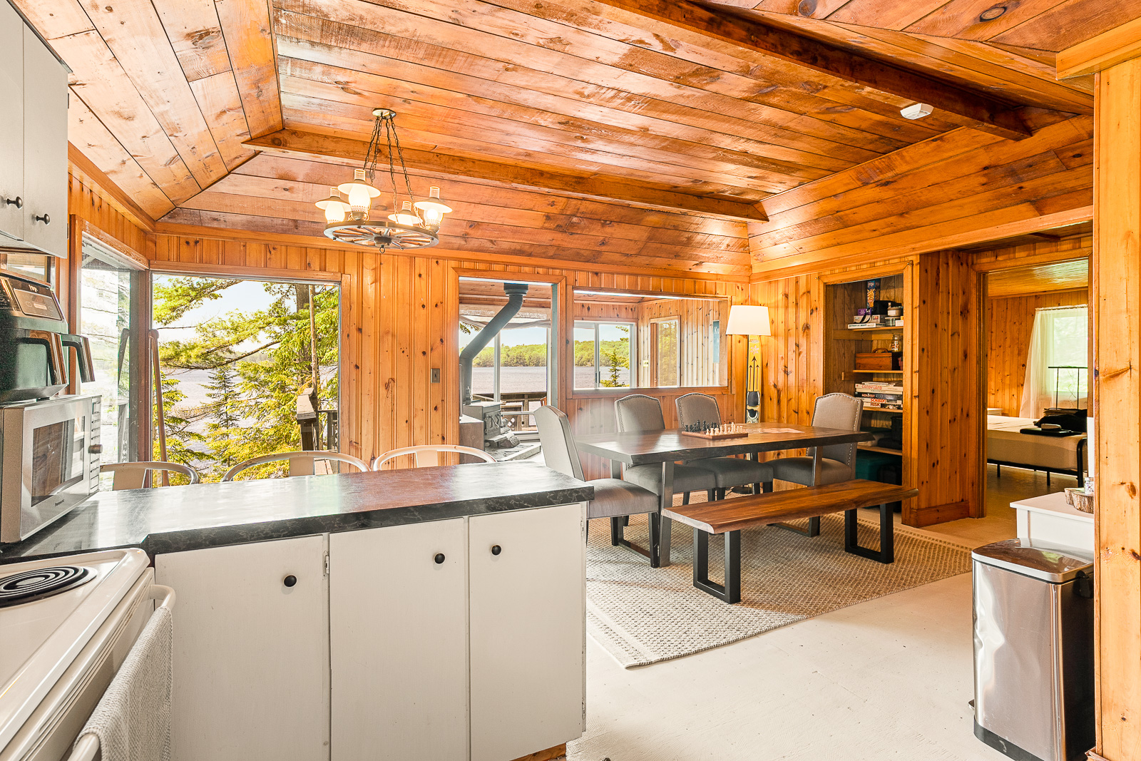 A white kitchen island sits in front of the cottage's dining room, a long table with bench seating
