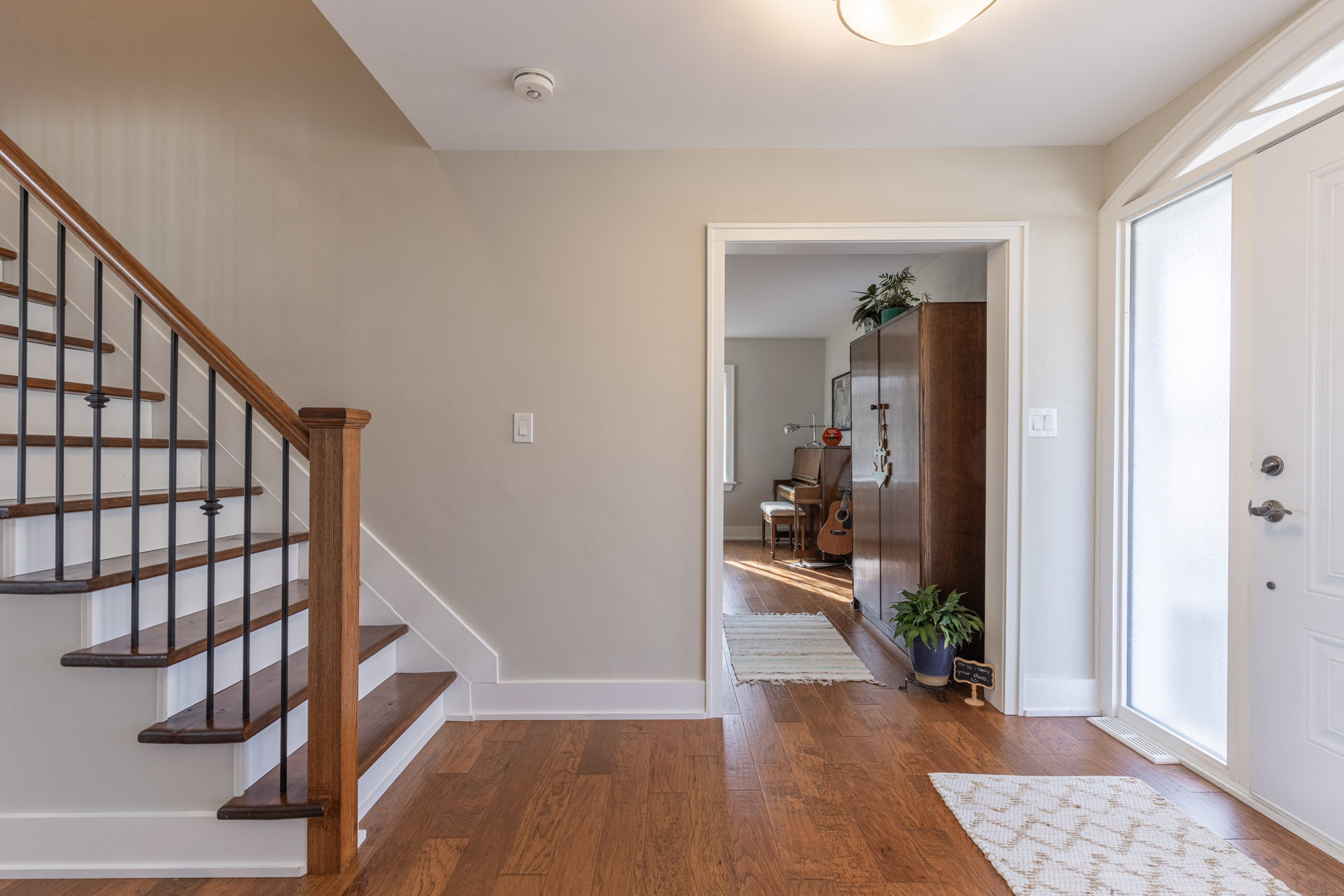 A white staircase with brown steps faces the white front door