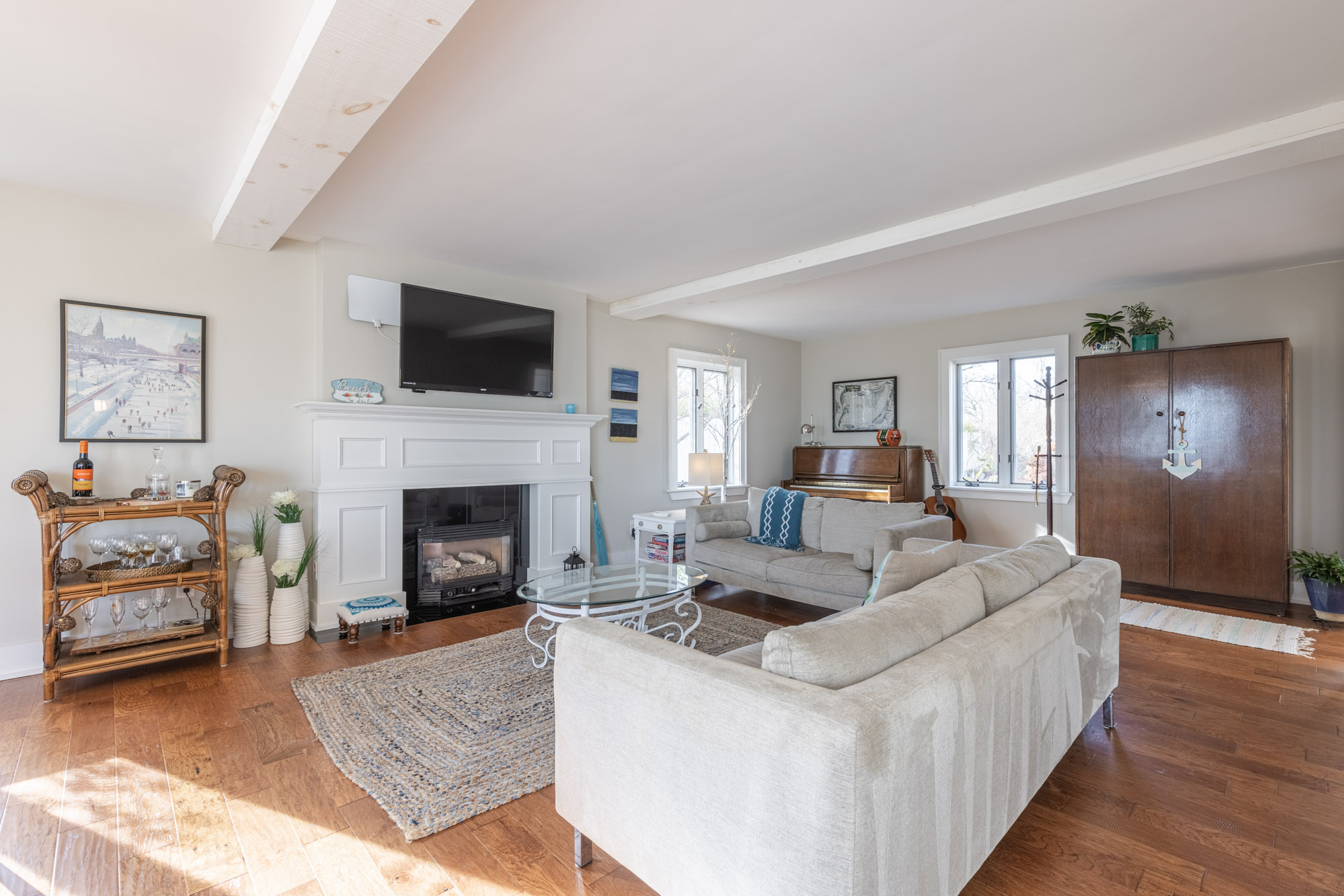 The beige couch faces the fireplace, bar cart and TV