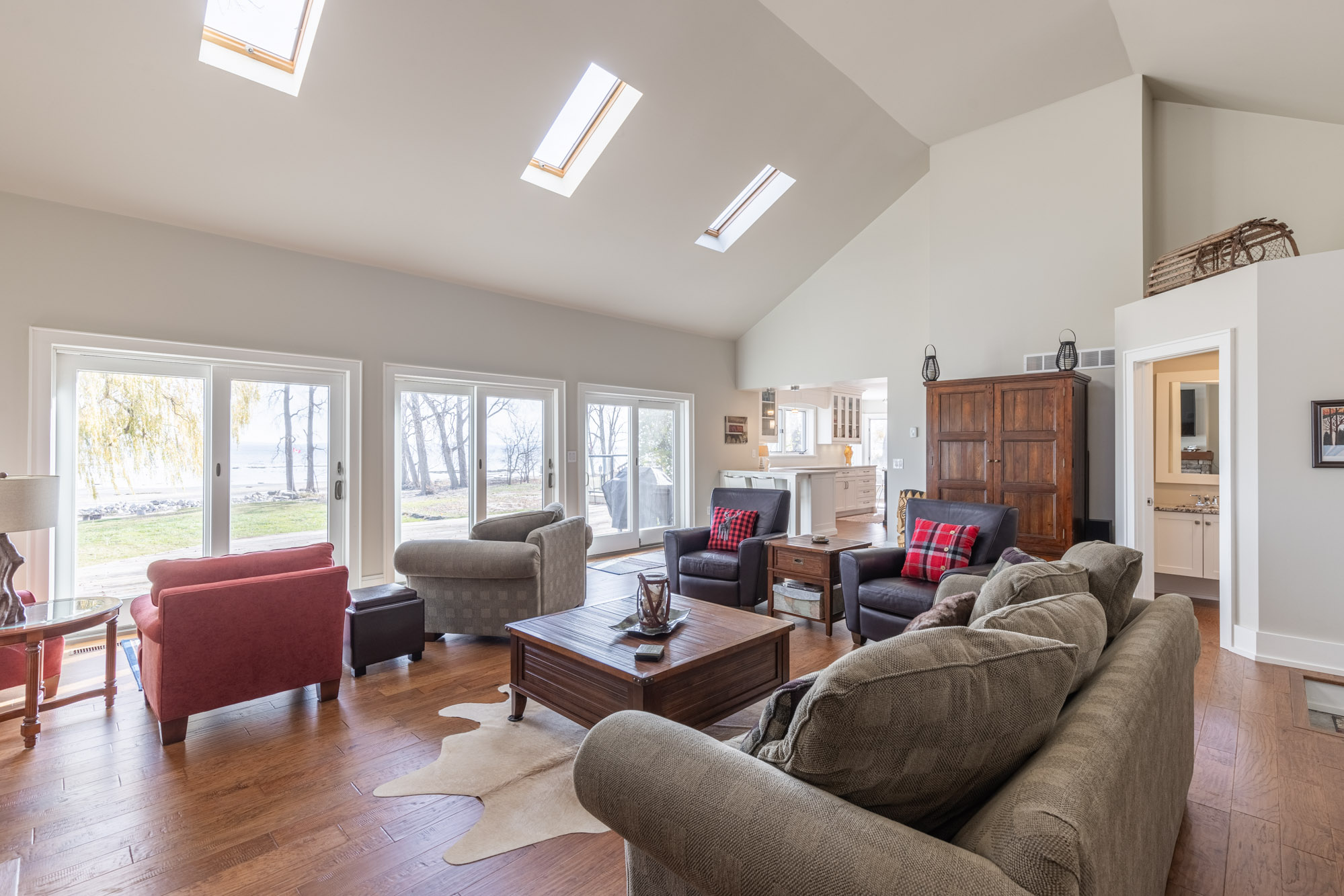 Some couches and chairs face the bright sliding doors that look out onto the lake