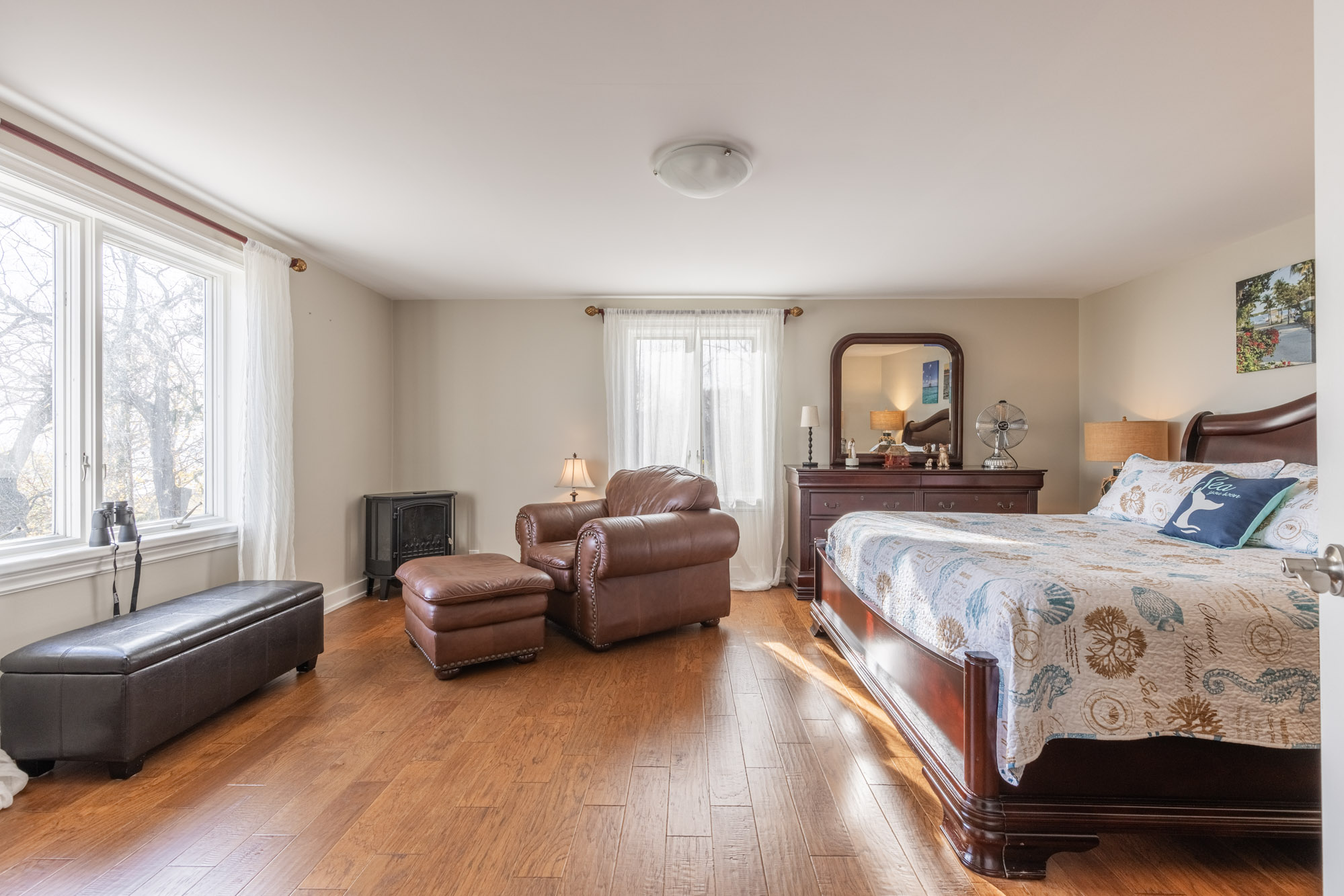 The bed faces large windows and a small black bench