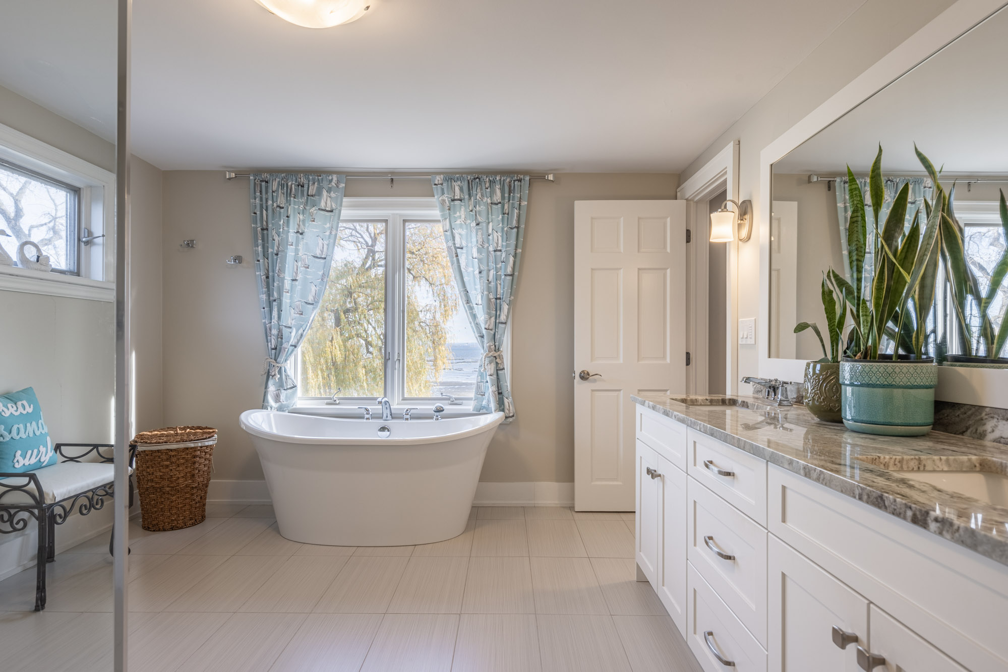 A bright bathroom with a large bathtub by a window, large vanity on the right