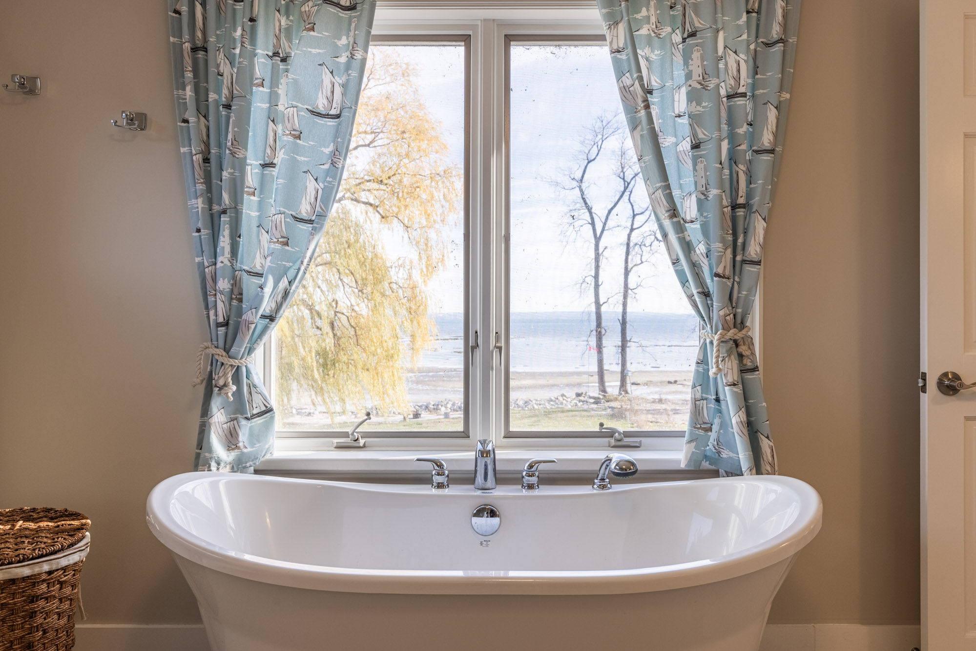 A white tub next to large windows with blue curtains