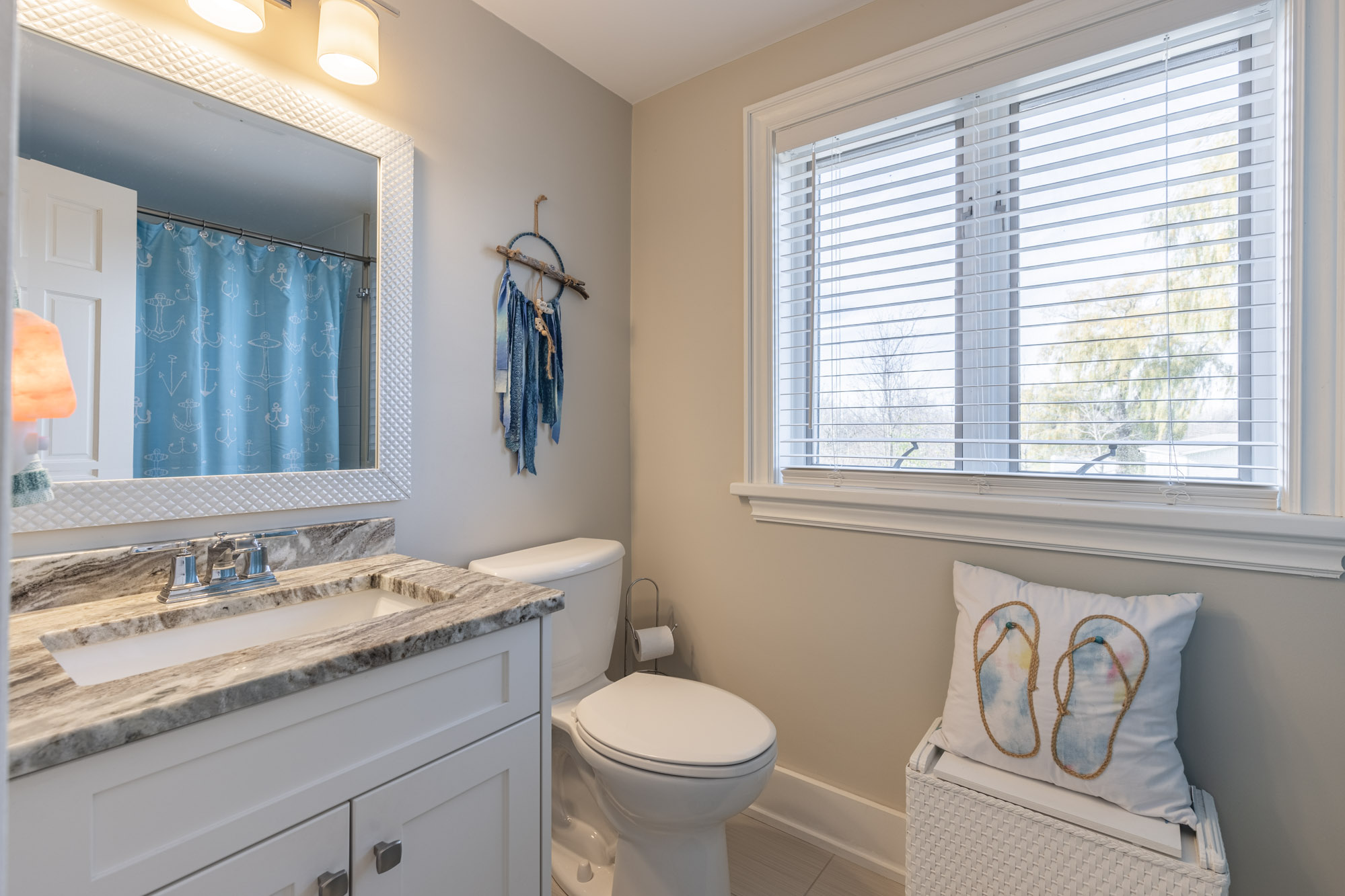 White bathroom with a white vanity with brown countertops, next to a toilet