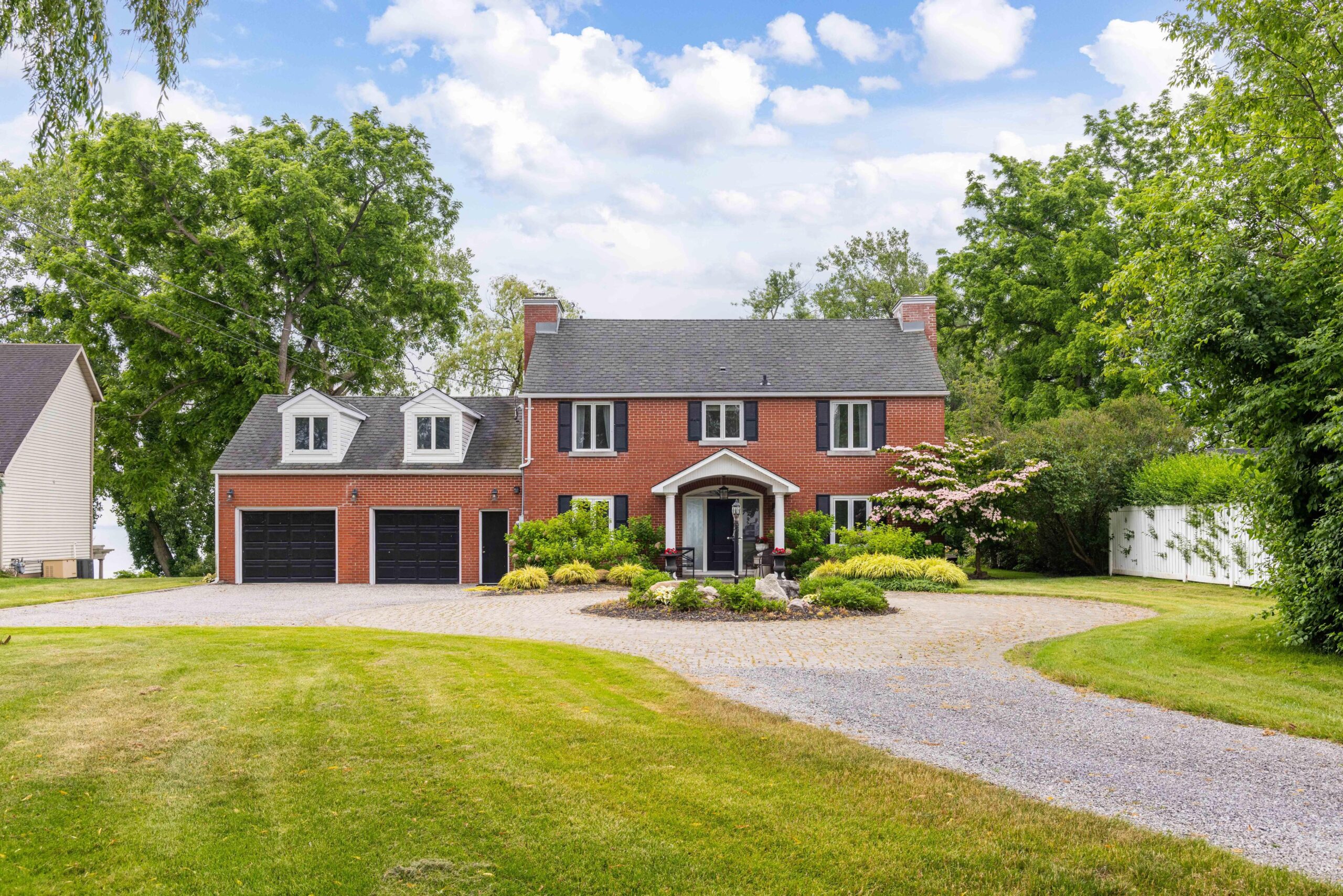 A driveway leads to a red brick house with a dark roof