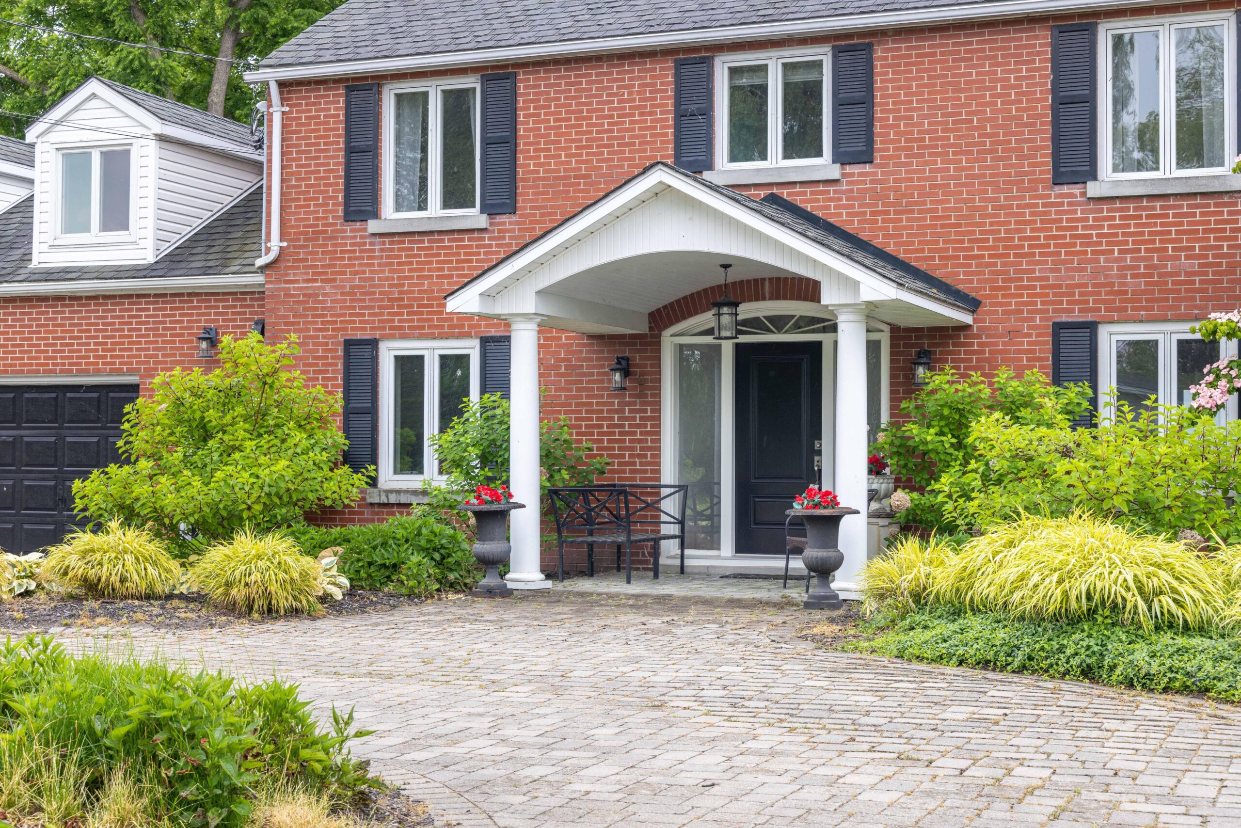 A red brick house with blue shutters and a white portico
