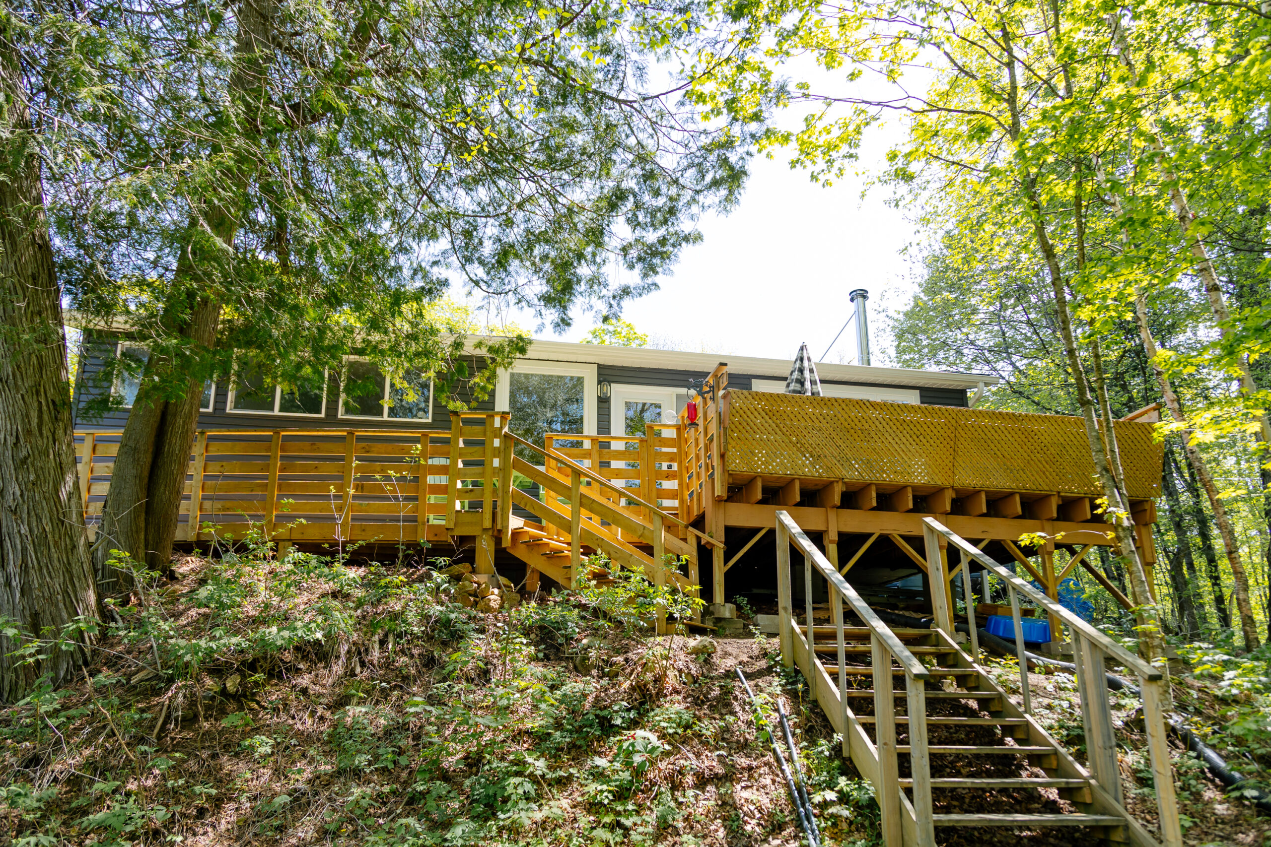A large wood back deck with steps that lead into the forest
