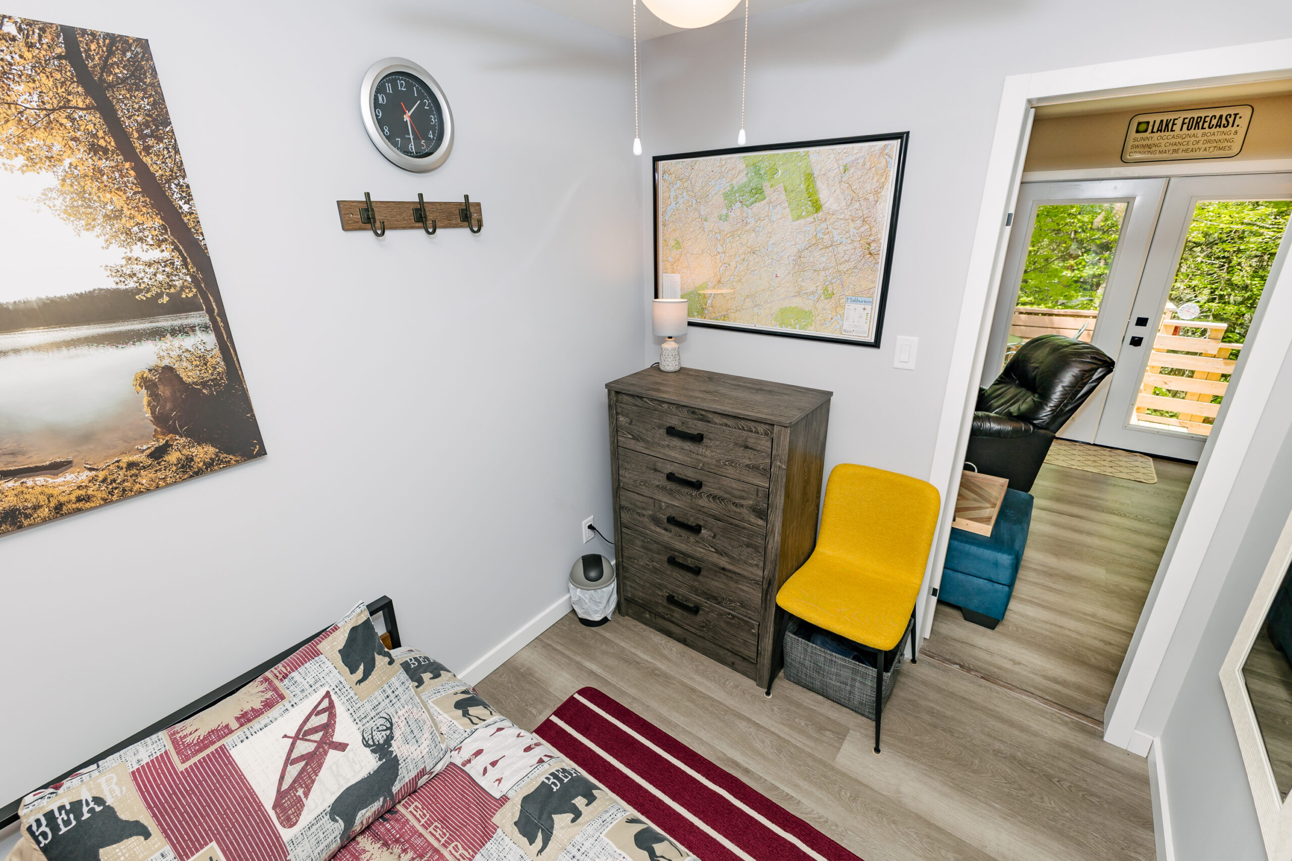 A grey dresser next to a yellow chair. A framed map hangs on the wall above