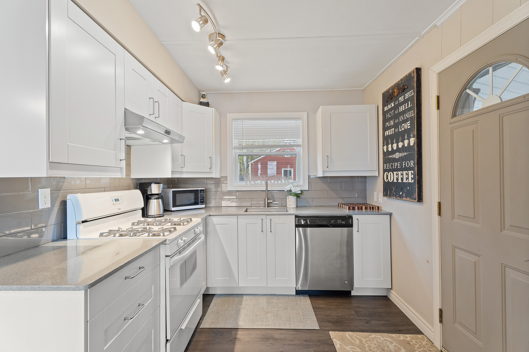 A small kitchen with white cabinetry, a dishwasher, and an oven with a gas stovetop.