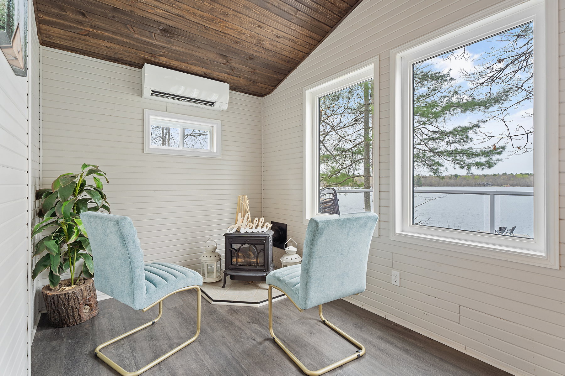 A cozy corner with a small wood stove. Two pale blue velvet chairs on gold metal frames sit in front of the wood stove.
