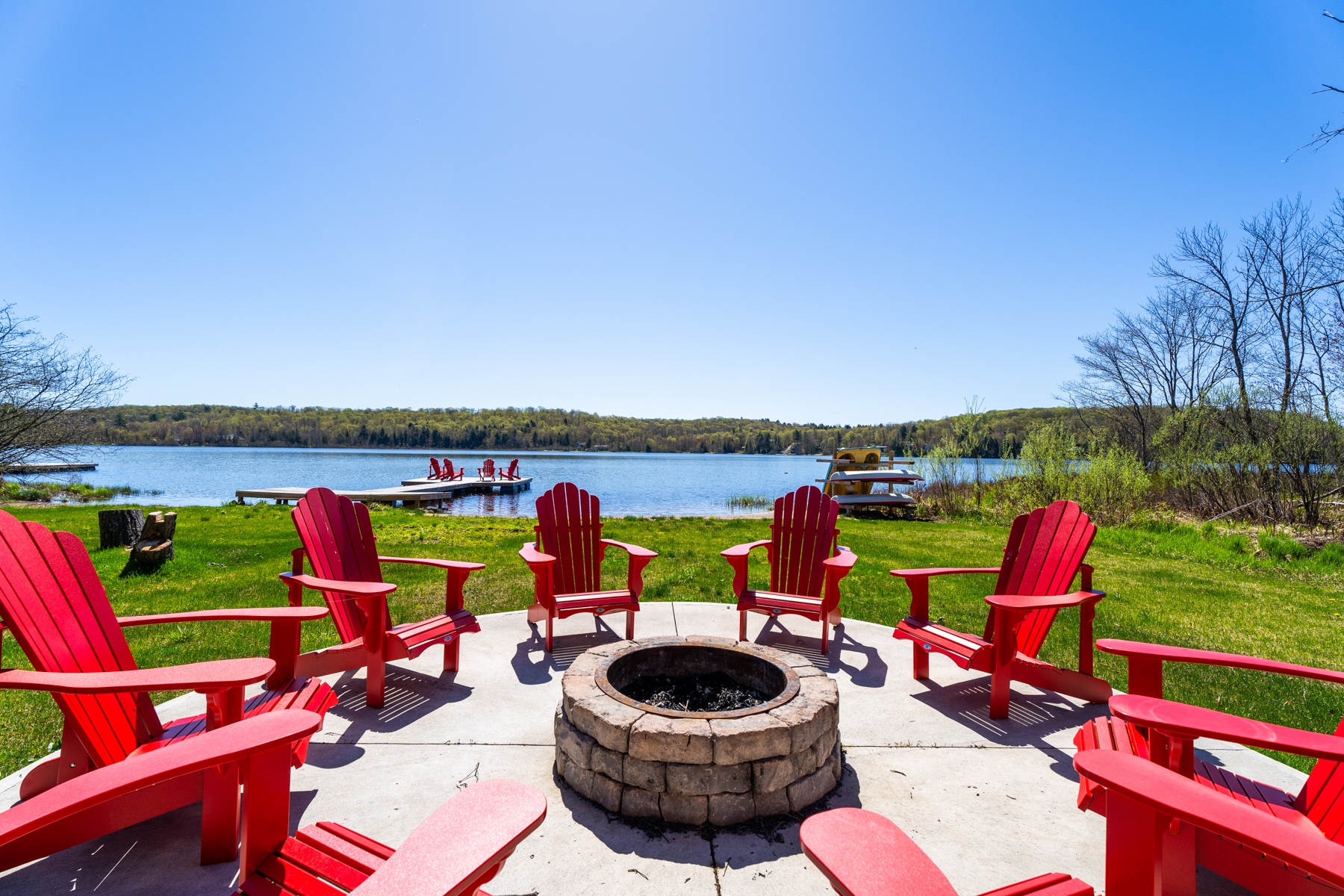 A stone fire pit area surrounded by red Muskoka chairs
