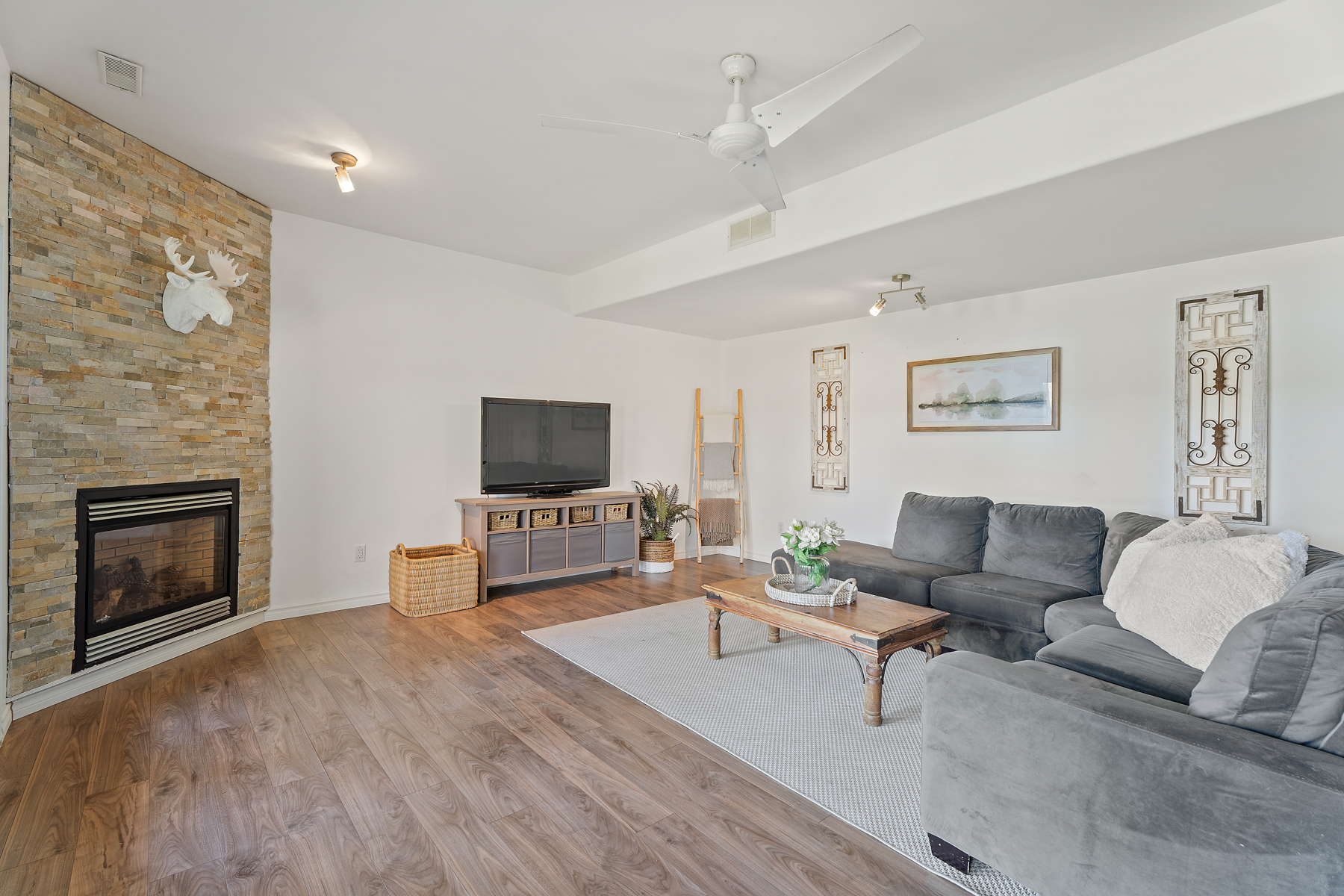 A grey love seat is perpendicular to a TV setup in the main living space