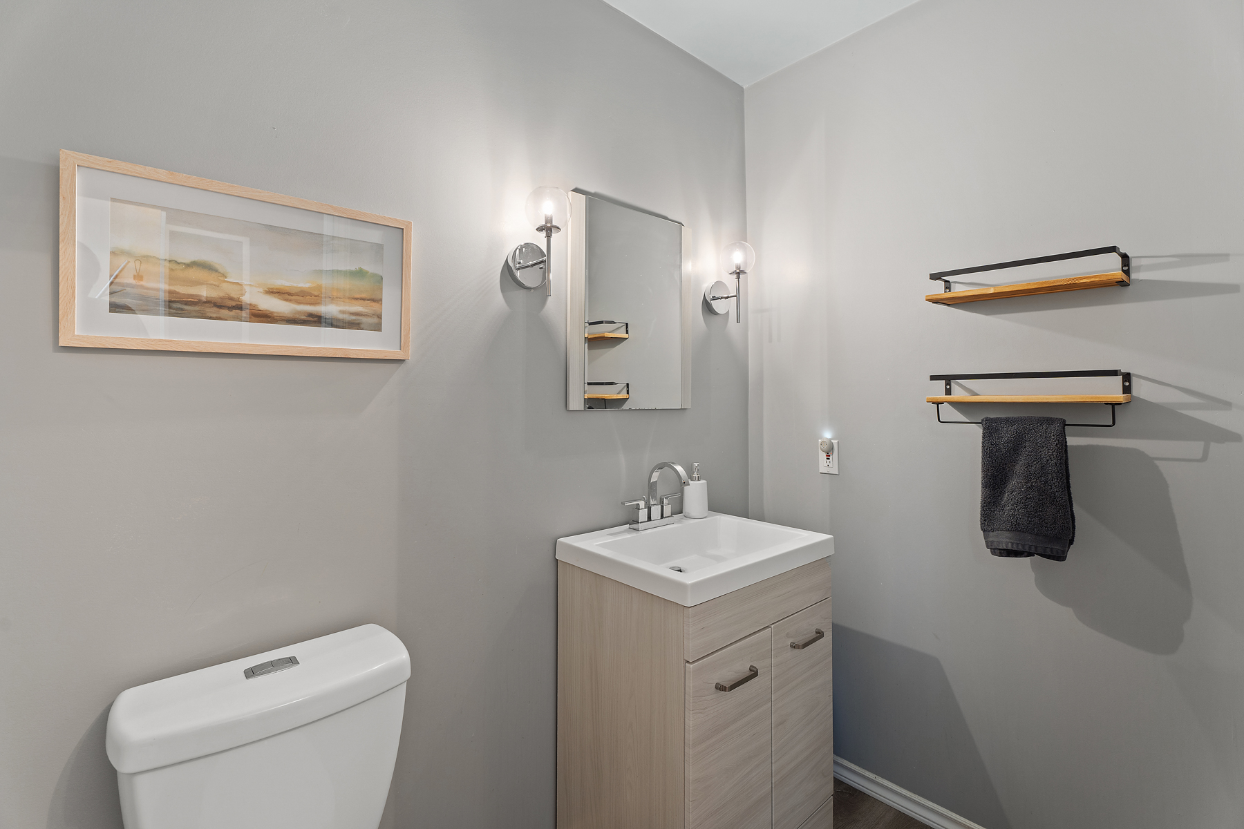 A grey bathroom with a white toilet next to the sink