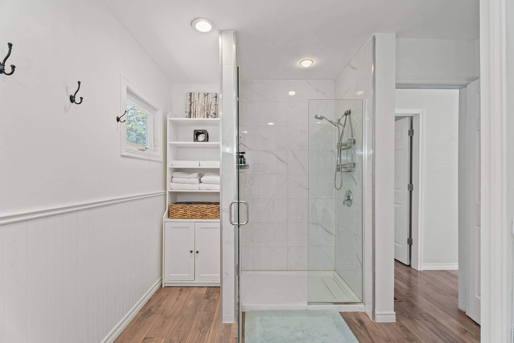 A white marble walk-in shower with glass doors