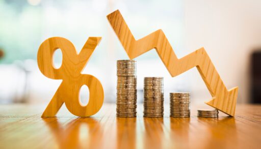 A wooden percentage mark is to the left of stacks of coins. An arrow pointing downwards hovers over the coins