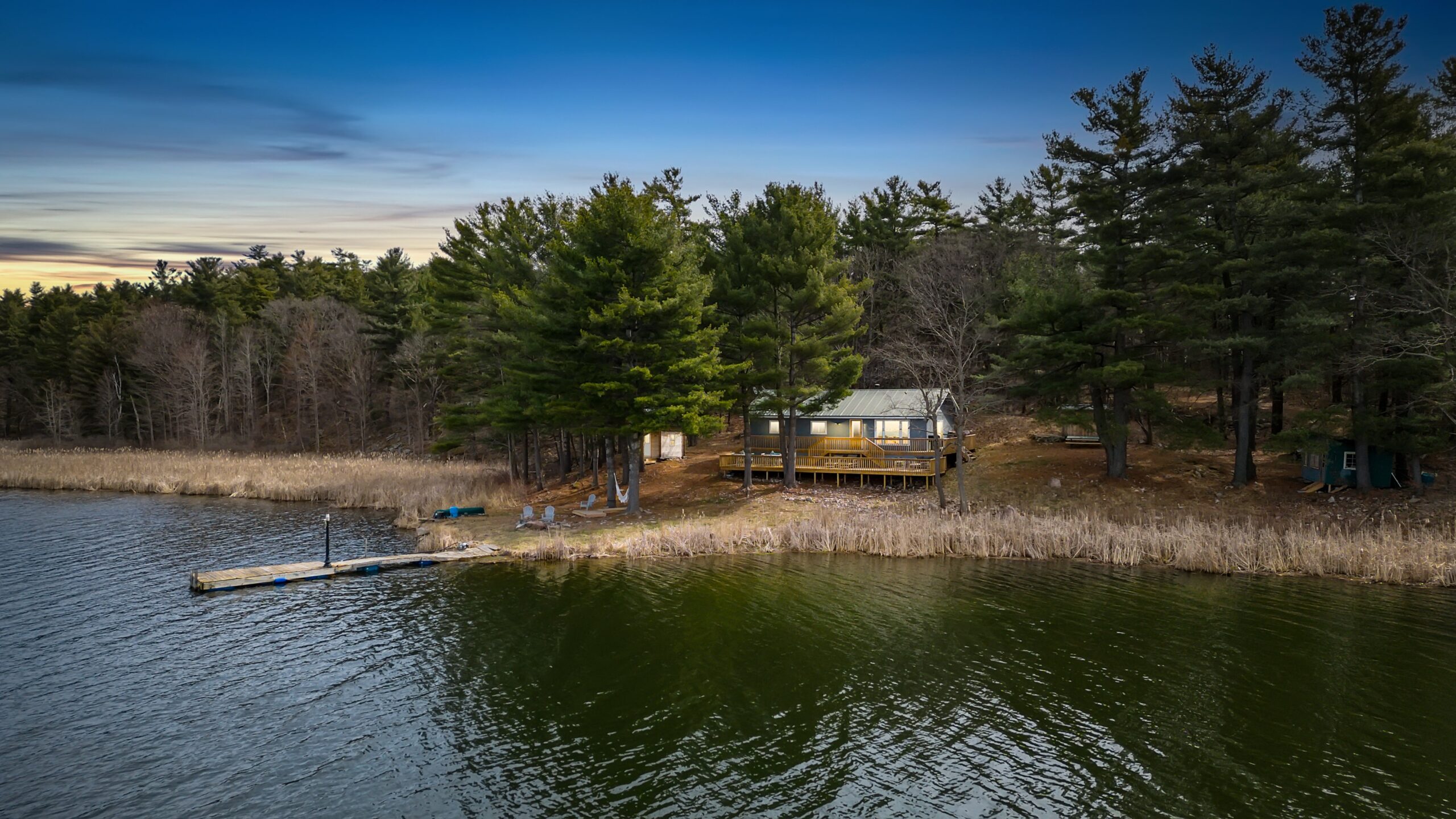 A small cottage on the shore of a lake glows at night
