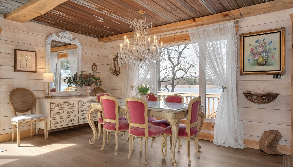 A white table with pink dining chairs next to a wide window