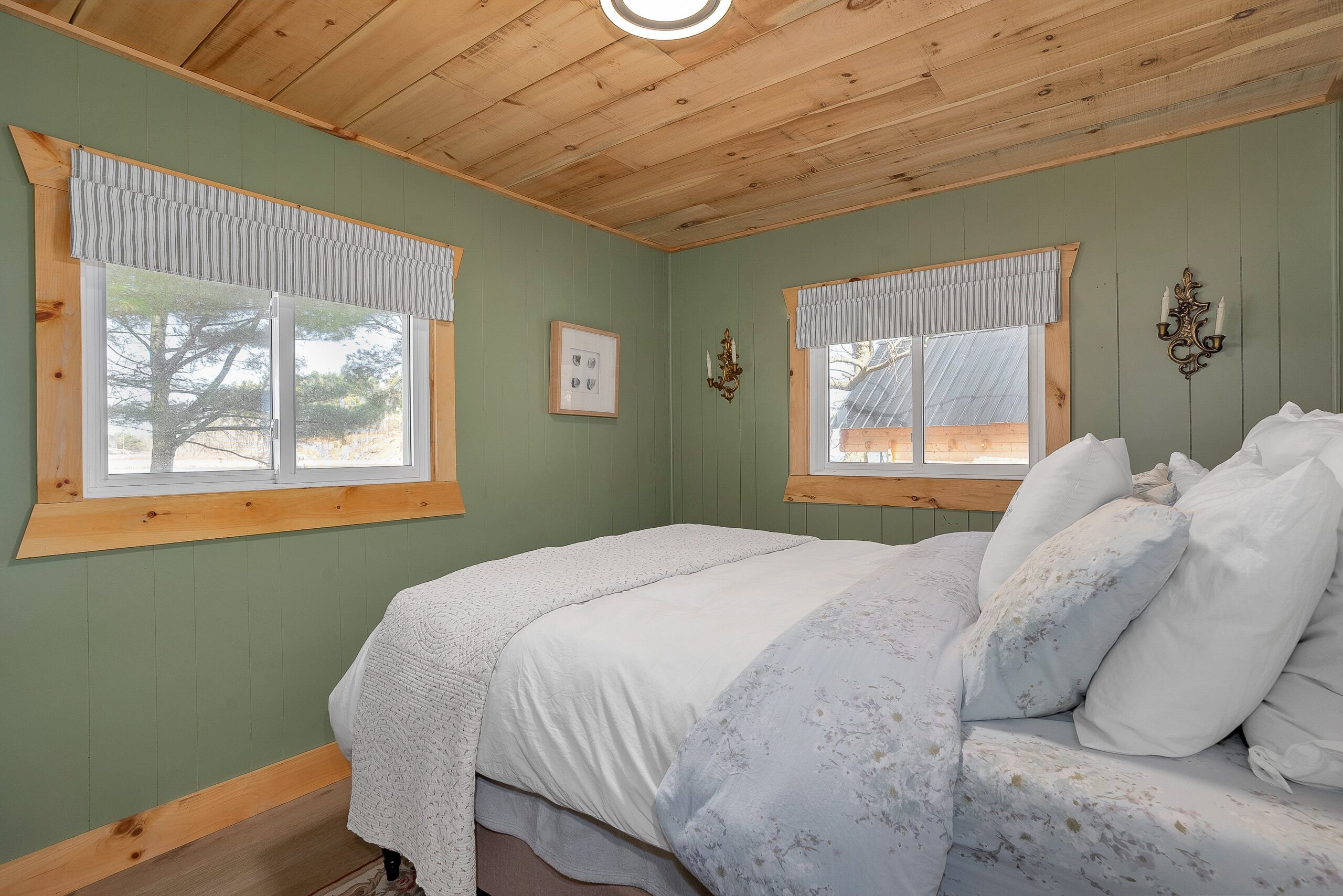 A large bed facing two windows in a green room