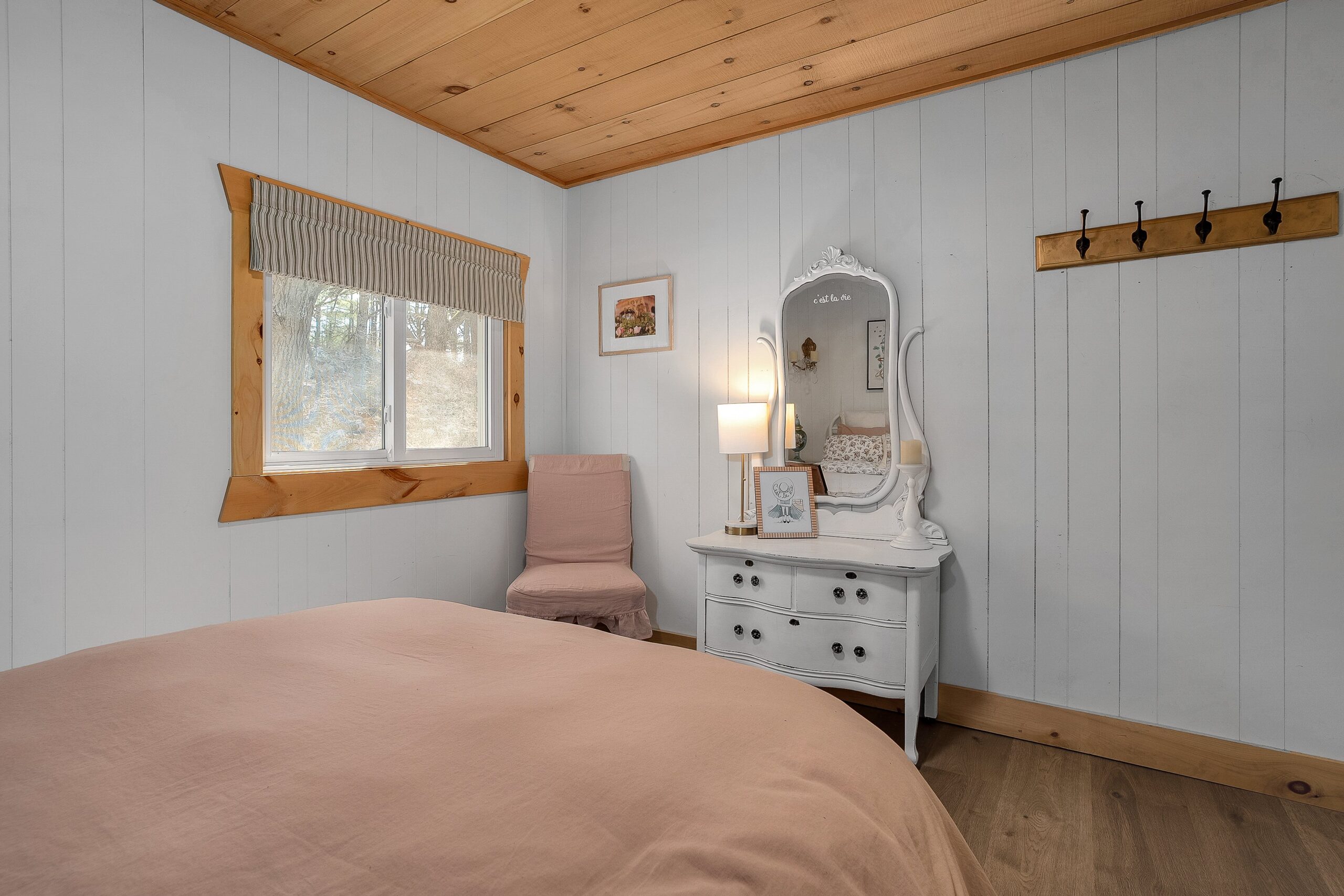 the end of a pink bed faces a white vanity in a white room