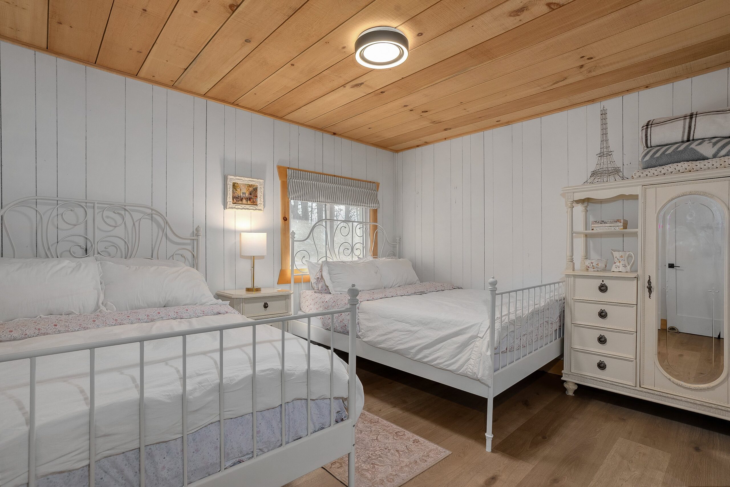Two white beds with a nightstand between them in a white room