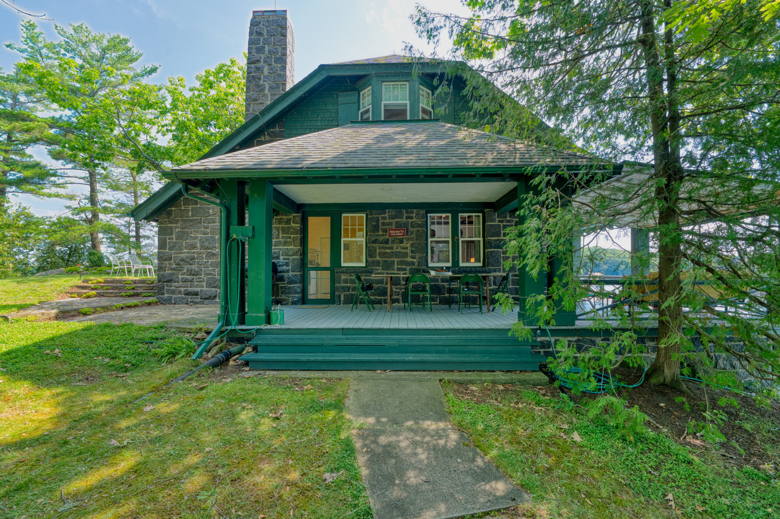 A stone cottage with a green covered porch