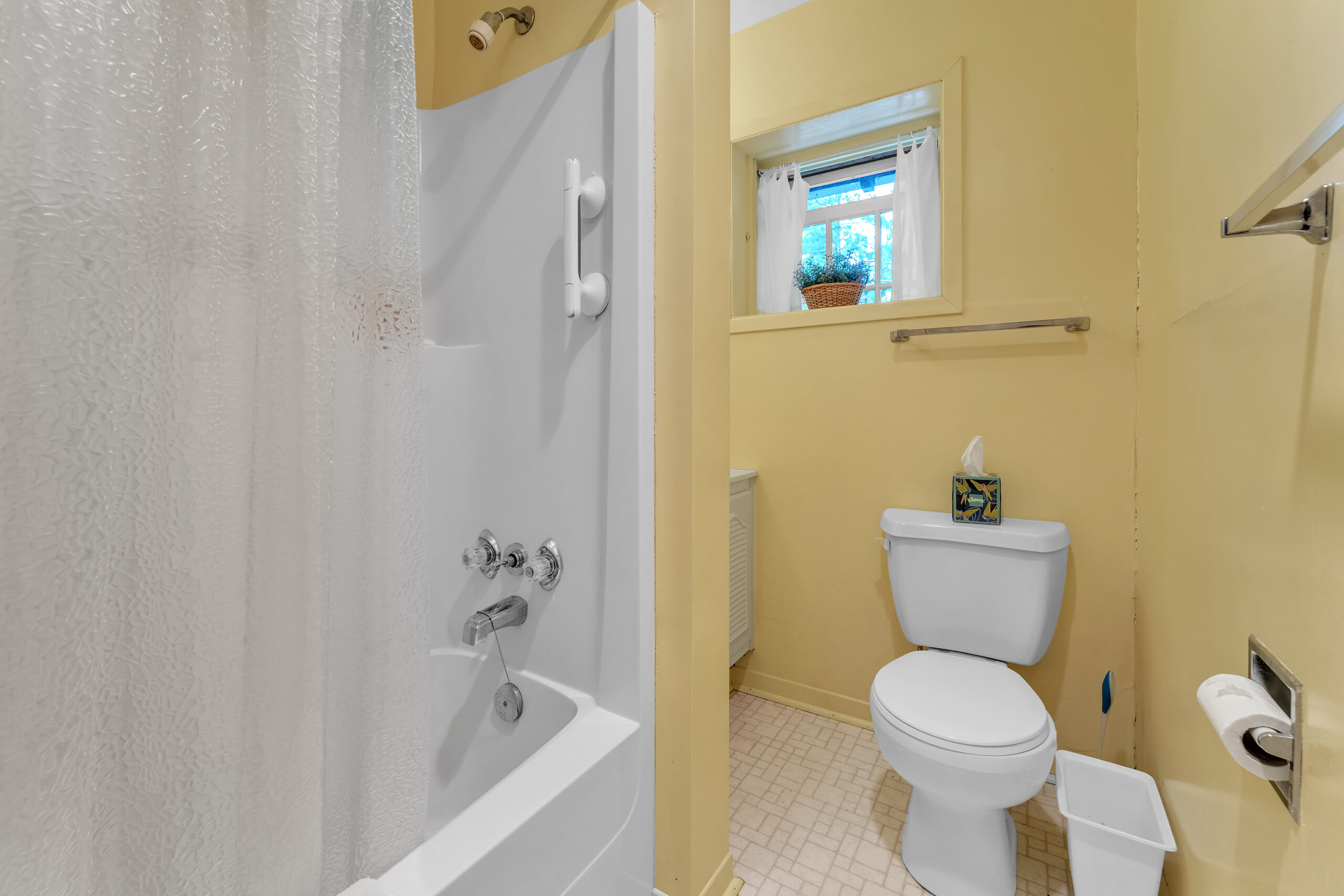 A yellow bathroom with a white tub and toilet