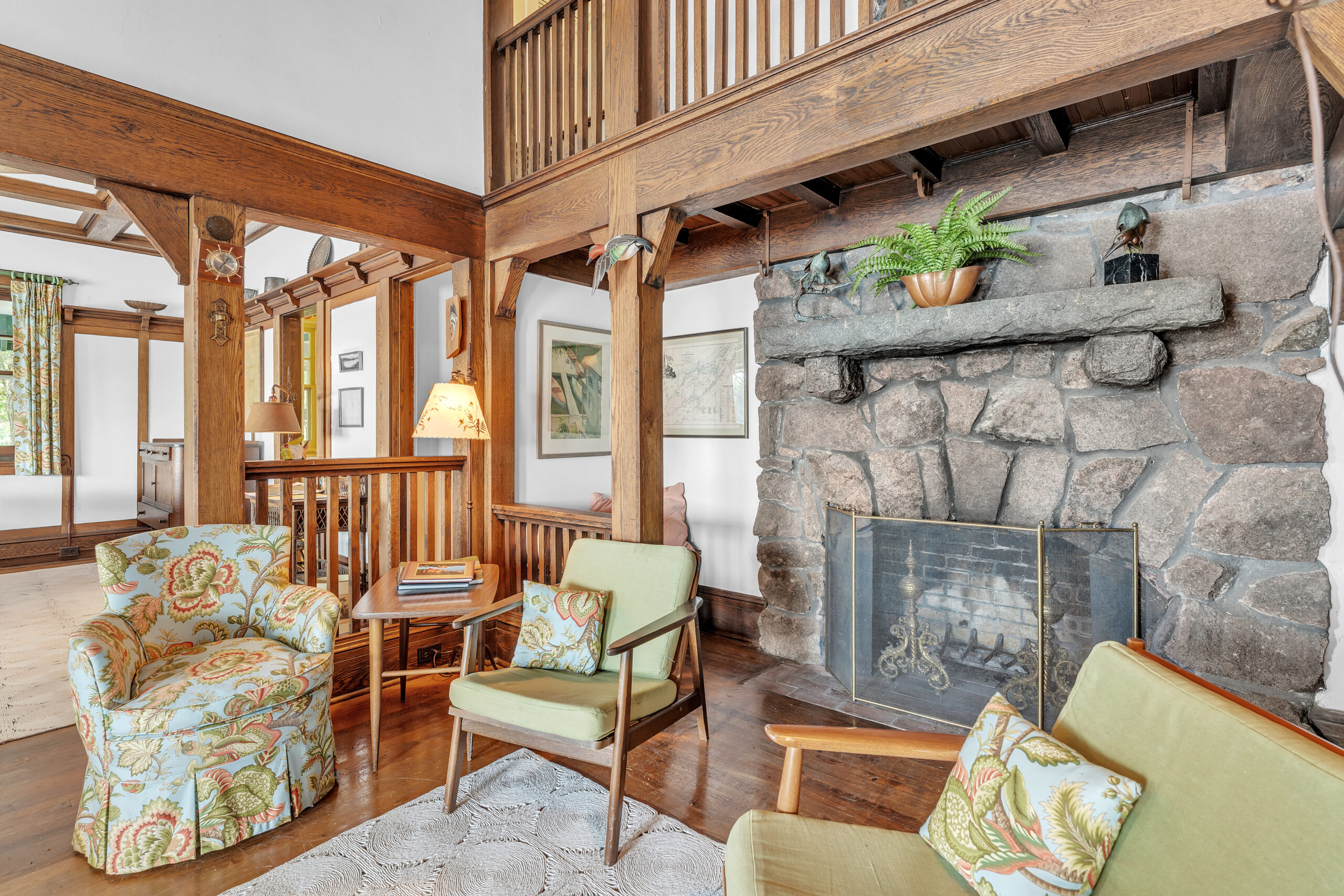 A side angle of the green chairs beside the stone fireplace