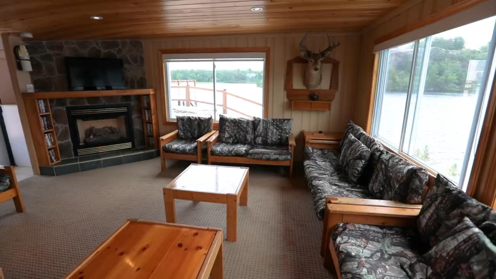 A carpeted room with wood tables and chairs with grey cushions