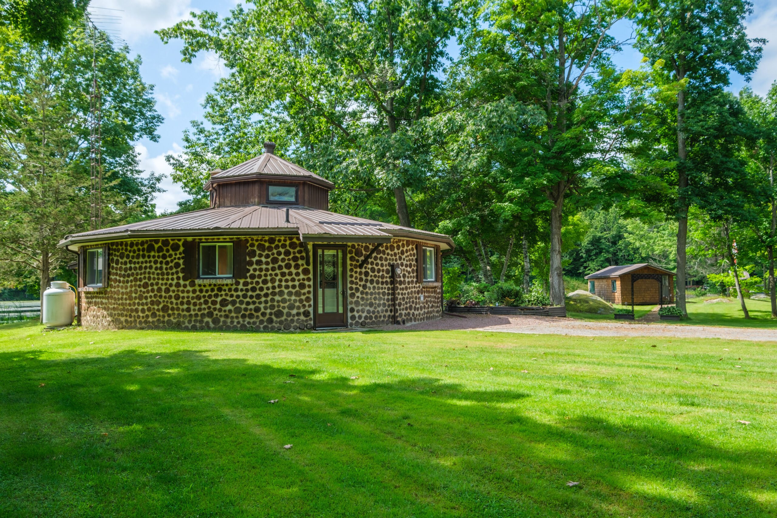A round stone cottage on a bright grassy lawn