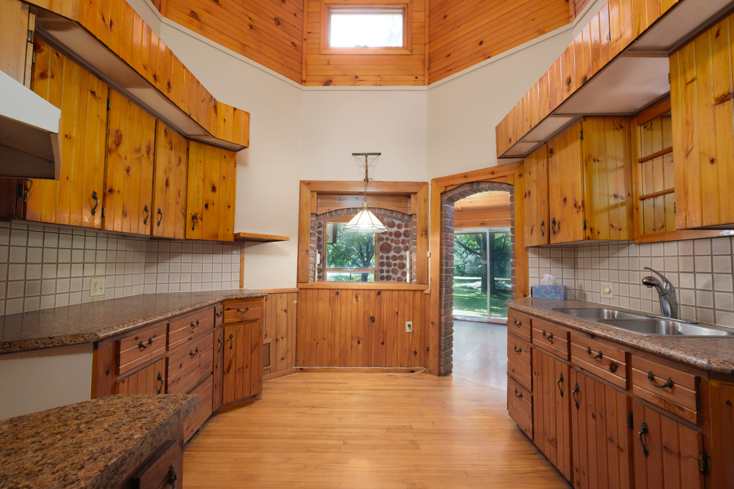 A rounded kitchen with wood floors and cabinets