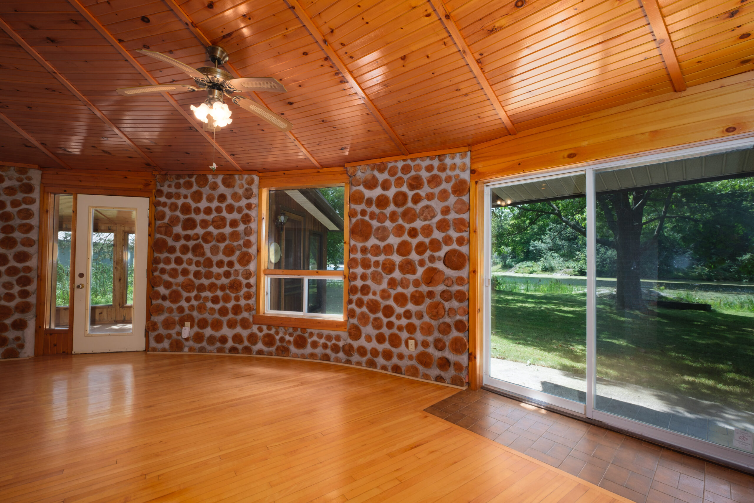 A rounded interior stone wall with large windows and a huge glass sliding door