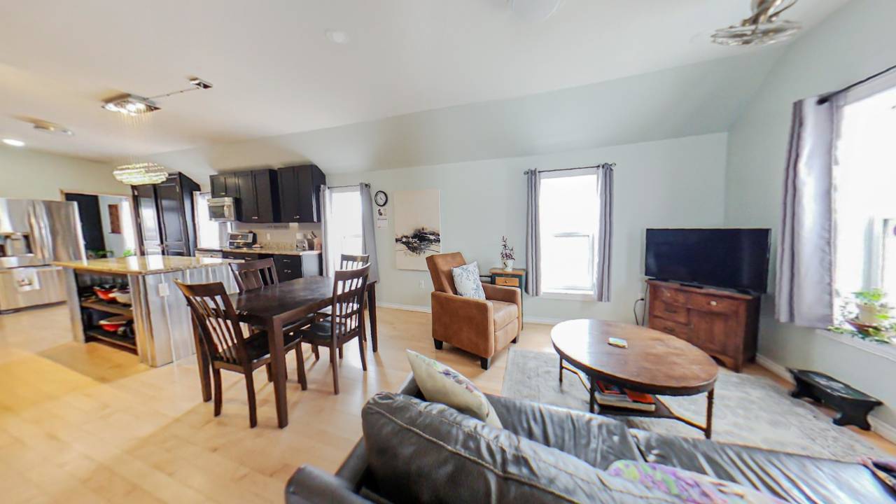A small wood dining table next to a family room with couches
