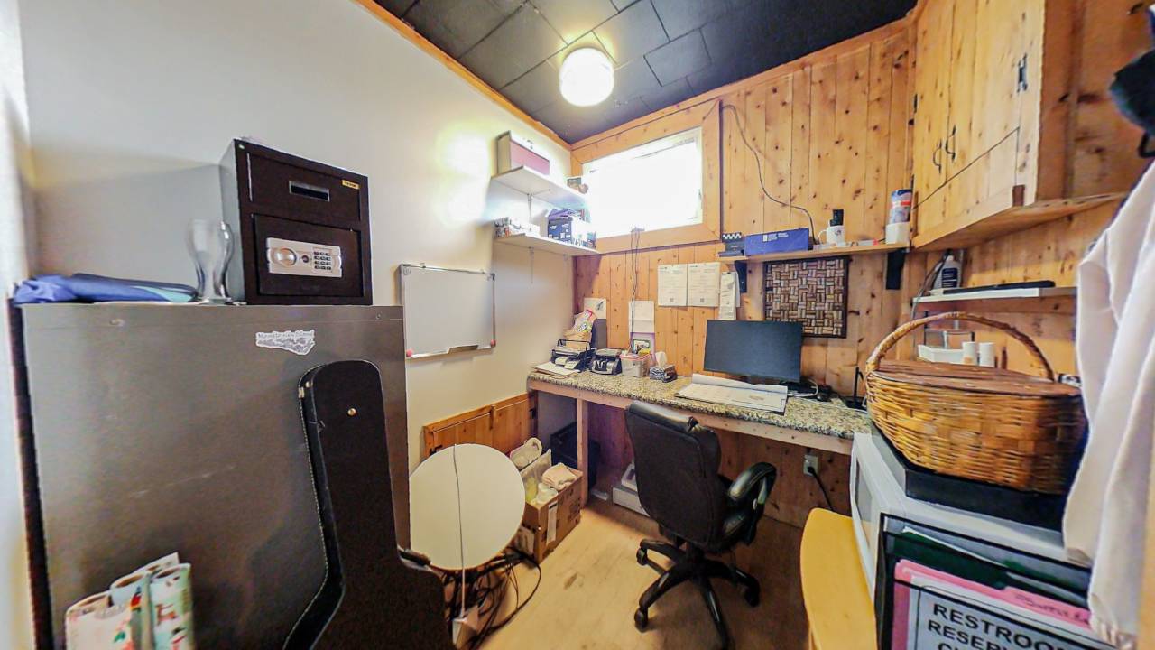 An unfinished office space with wood walls and a desk with a computer