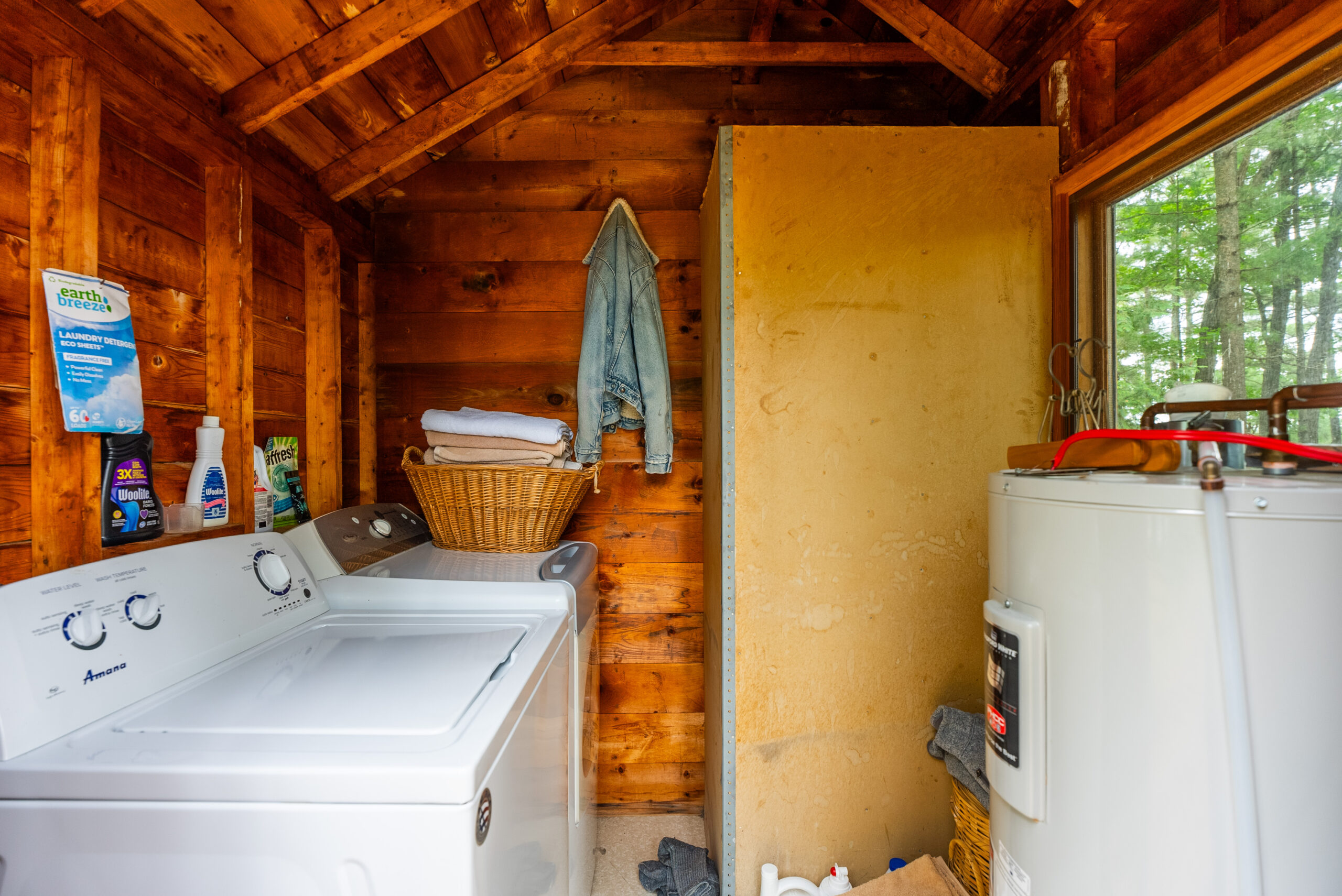 A white laundry machine in a wood room