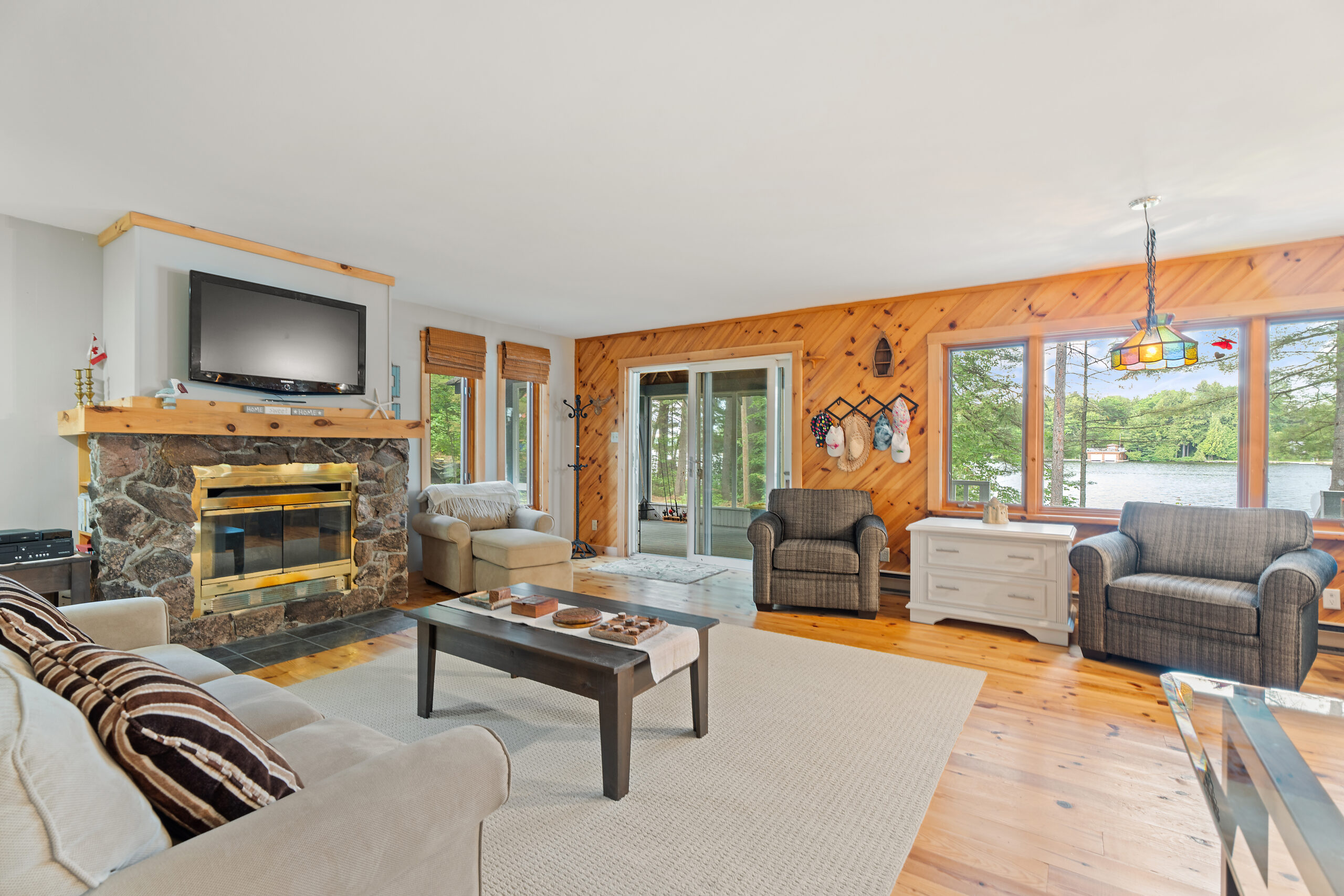A coffee table on a white carpet faces two brown loveseats on the far wall. To the left, a large stone fireplace