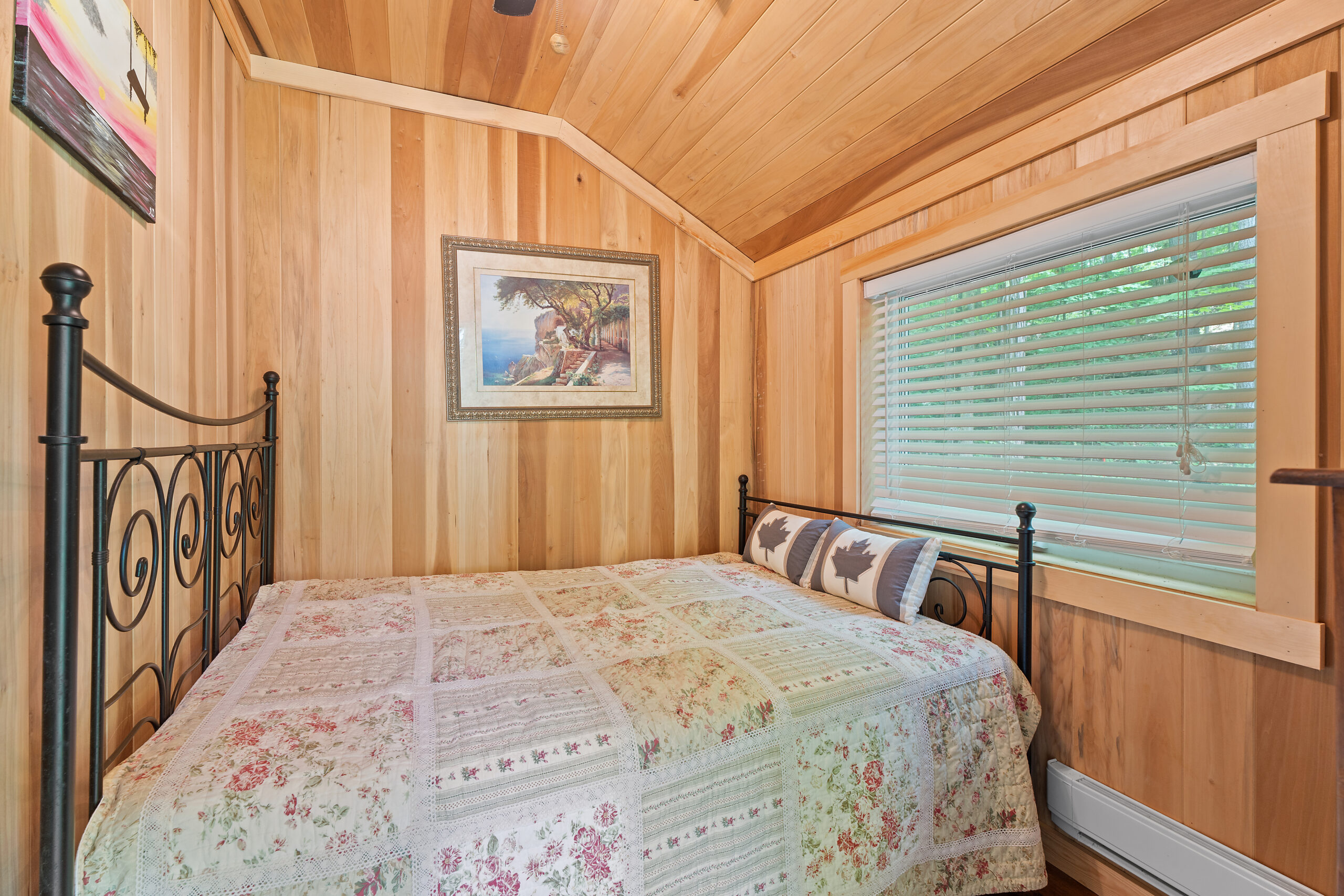 A wood panelled room with a quilted bed that fills up the space
