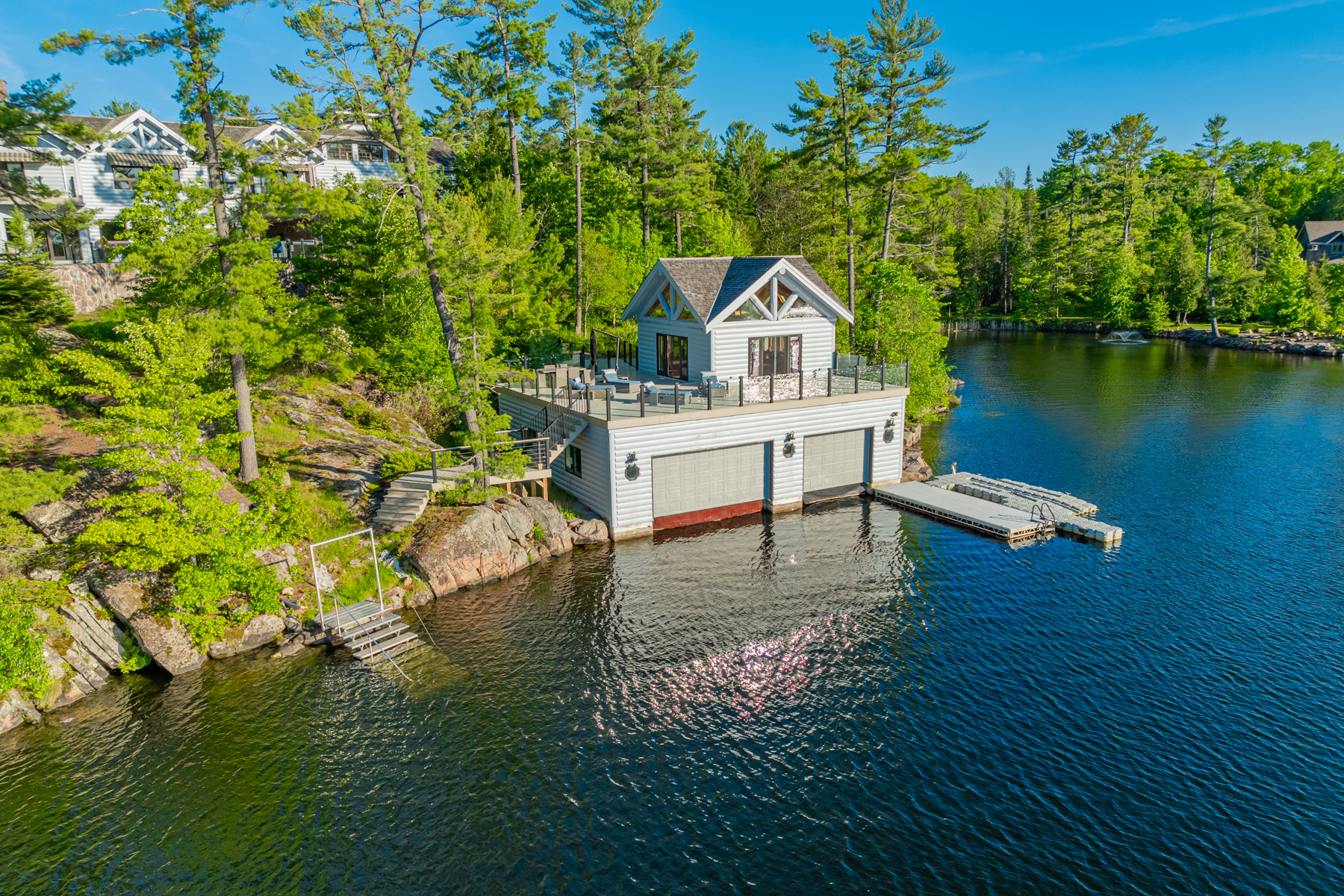 A grey boathouse on the lake surrounded by trees