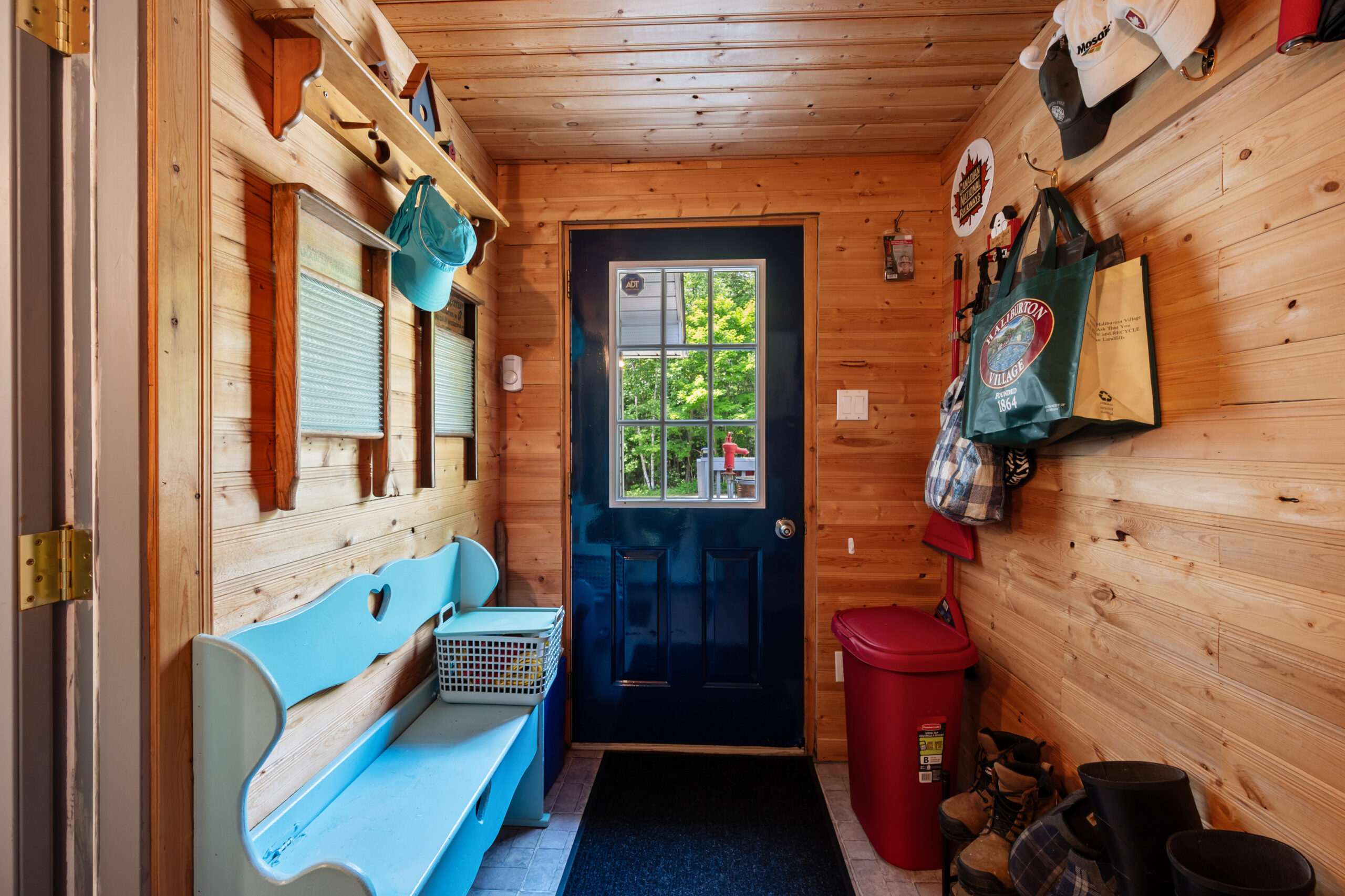 A blue door leads to a wood-panelled mudroom with a bench on the left