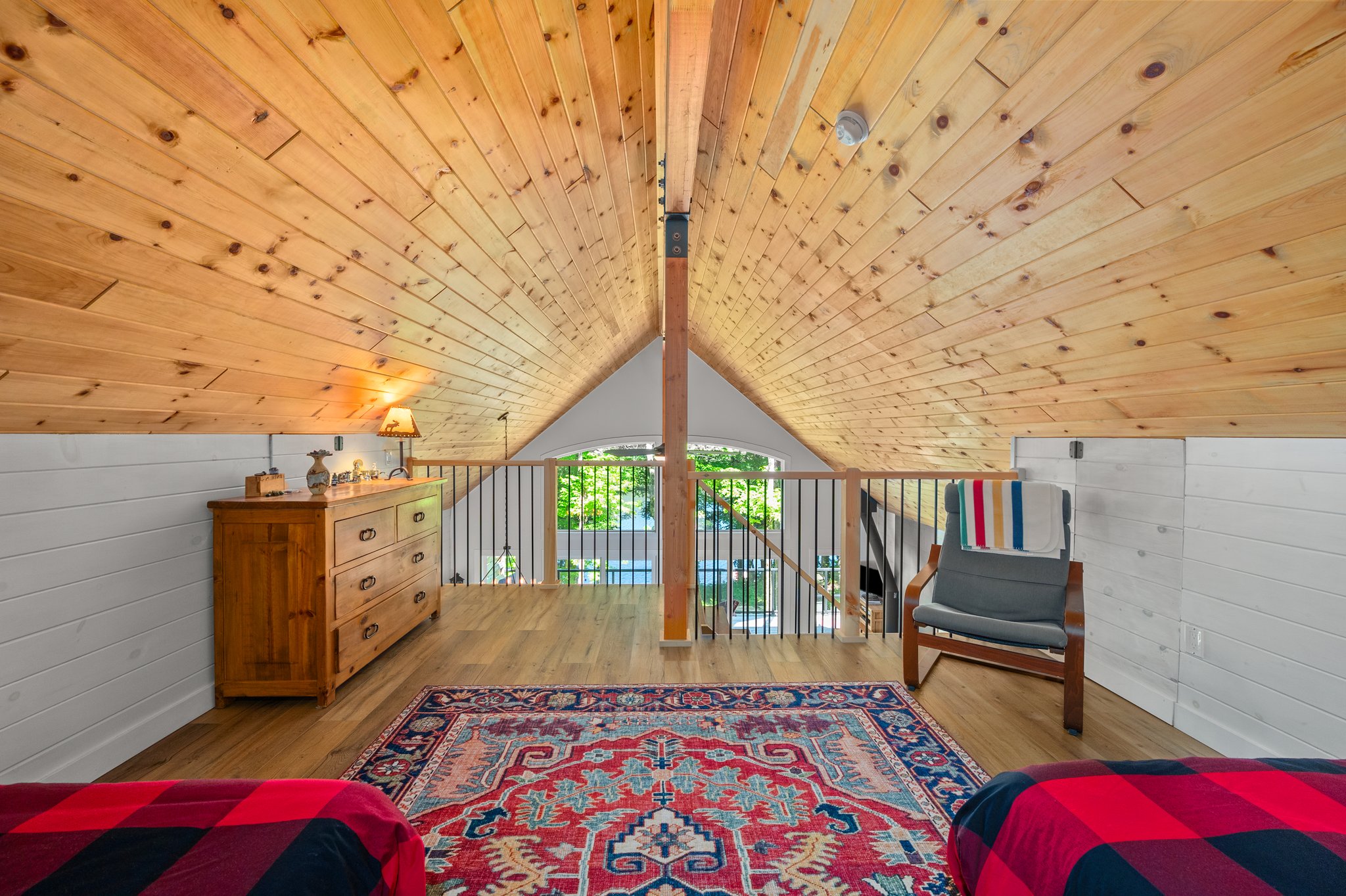 A large patterned carpet faces a railing. Wood-panelled vaulted ceilings above