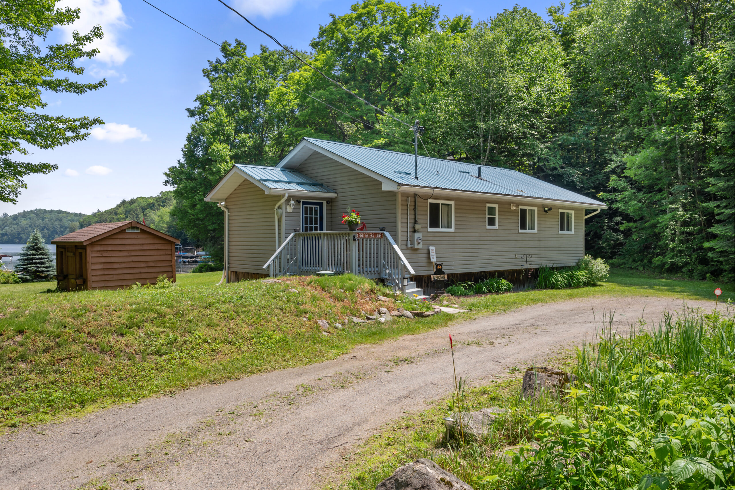 A grey panelled cottage next to a driveway